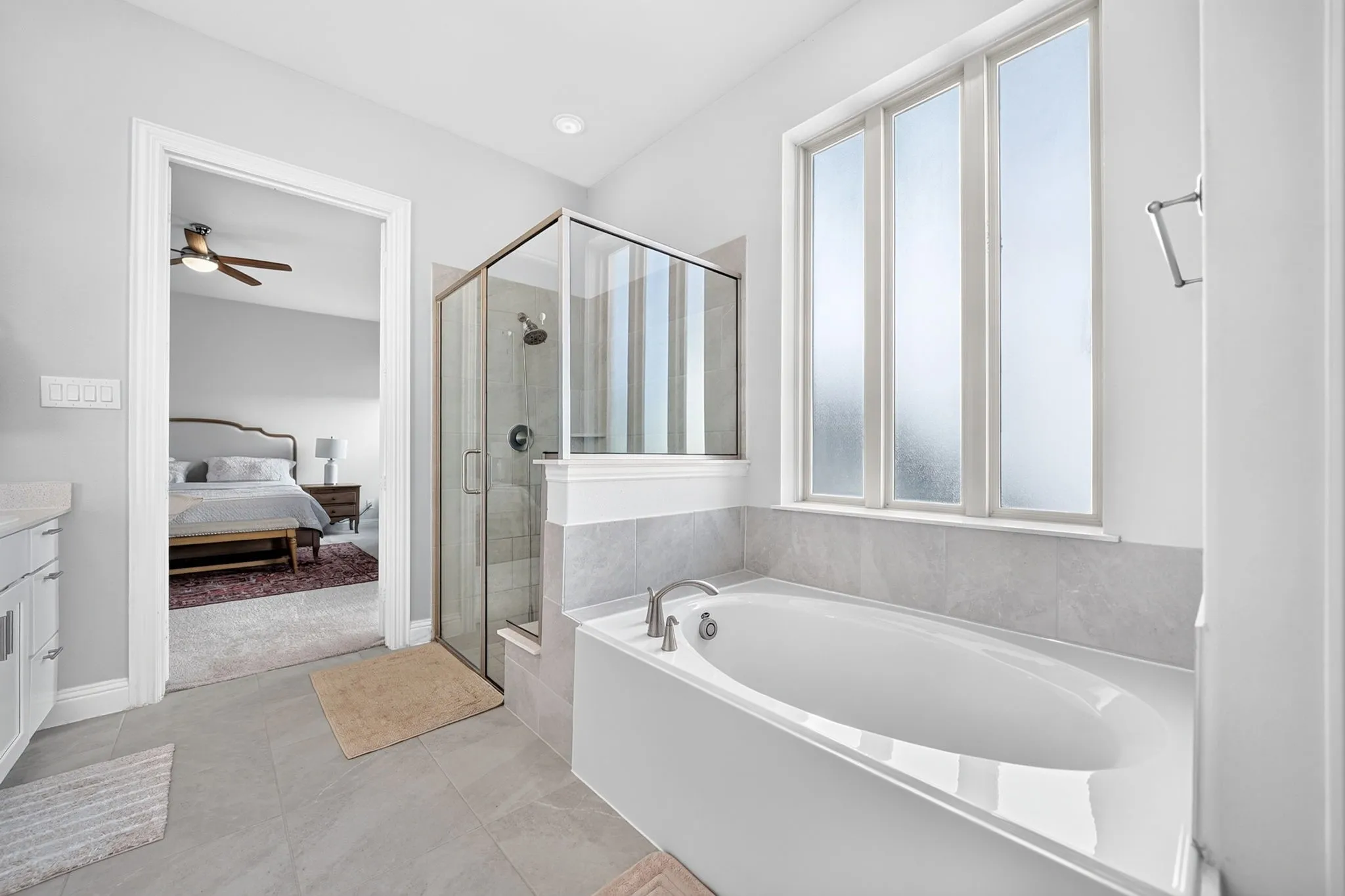 Soaking tub with a wall-mounted faucet, glass-enclosed shower, and a triple-pane window