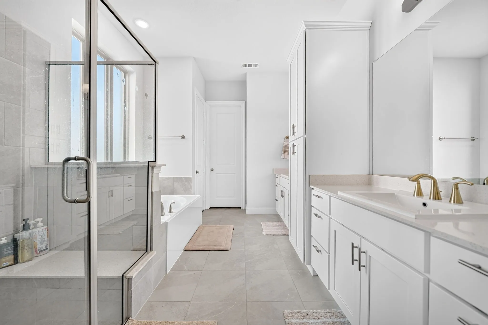 Dual vanity with light-toned countertops, white cabinetry, and gold-finish faucets