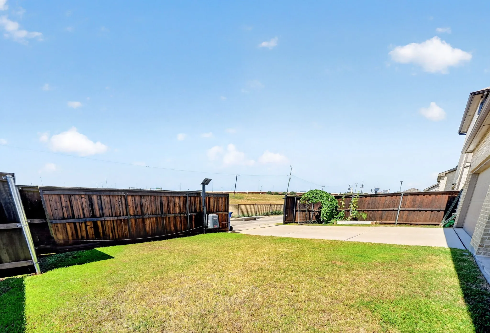 Expansive backyard featuring a manicured lawn, concrete patio, and a wood privacy fence