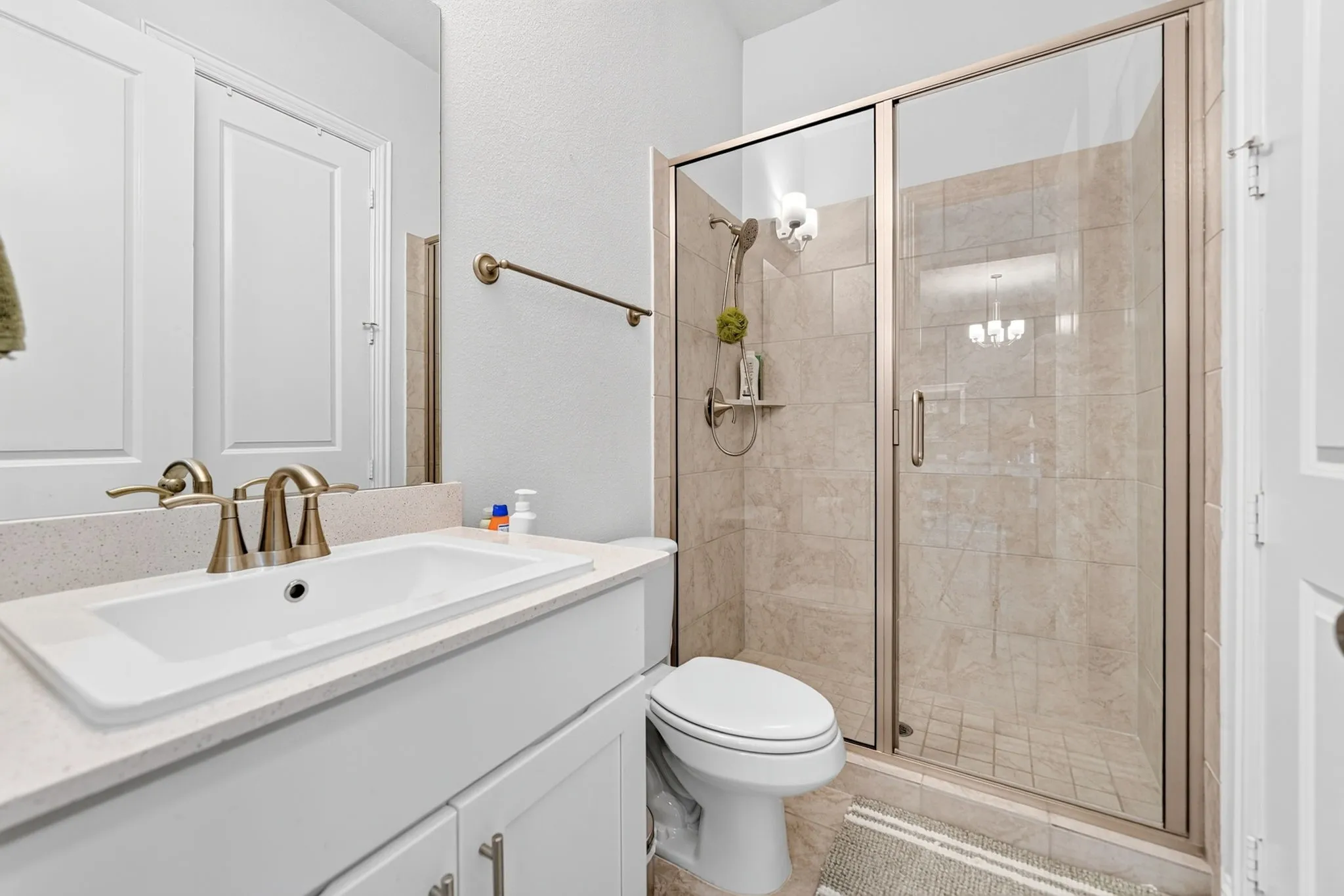 White vanity with integrated sink, bronze-finish faucet, and light-toned countertop