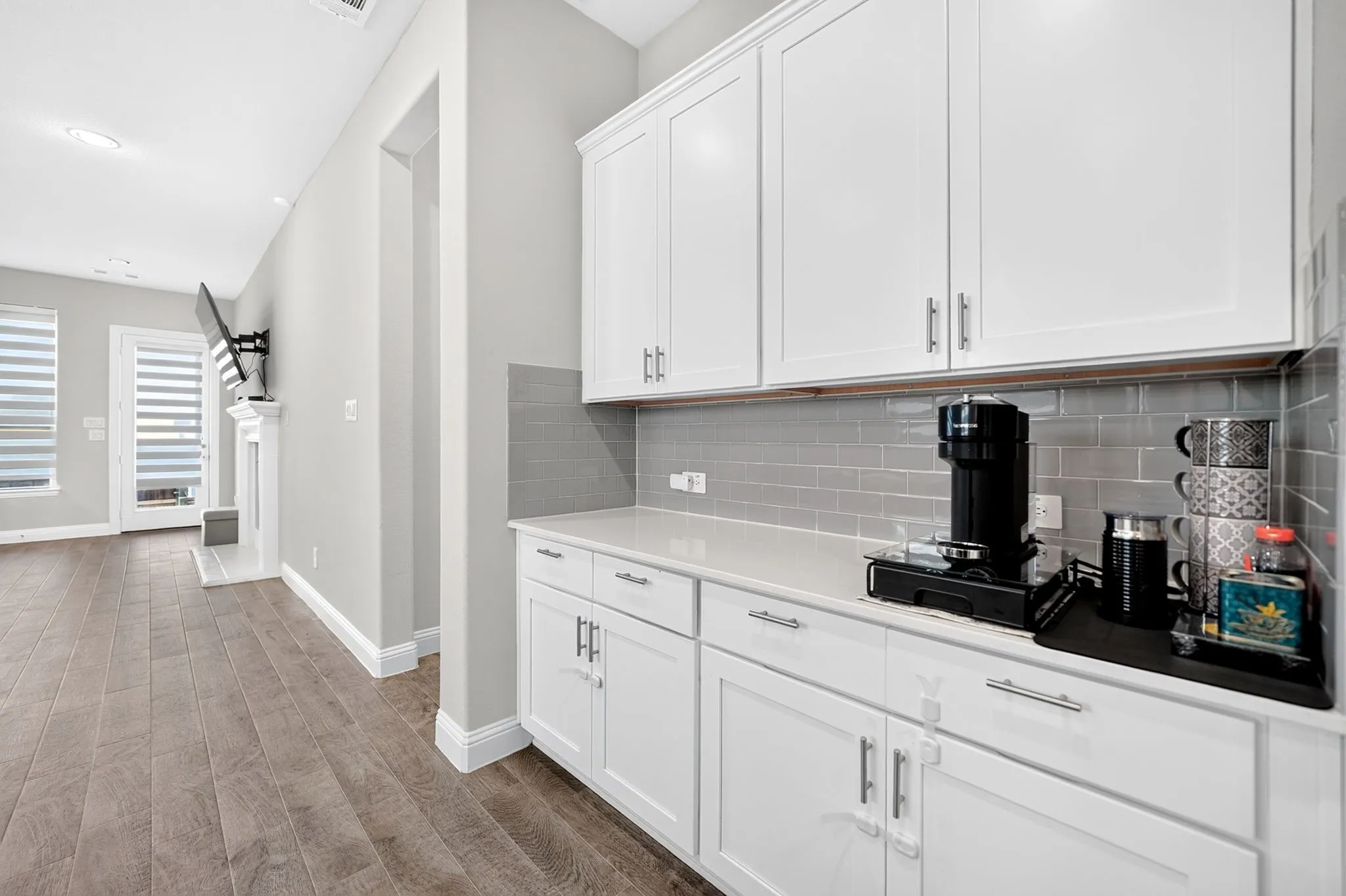 Integrated beverage station featuring white cabinetry, quartz-finish countertop, and gray subway tile backsplash