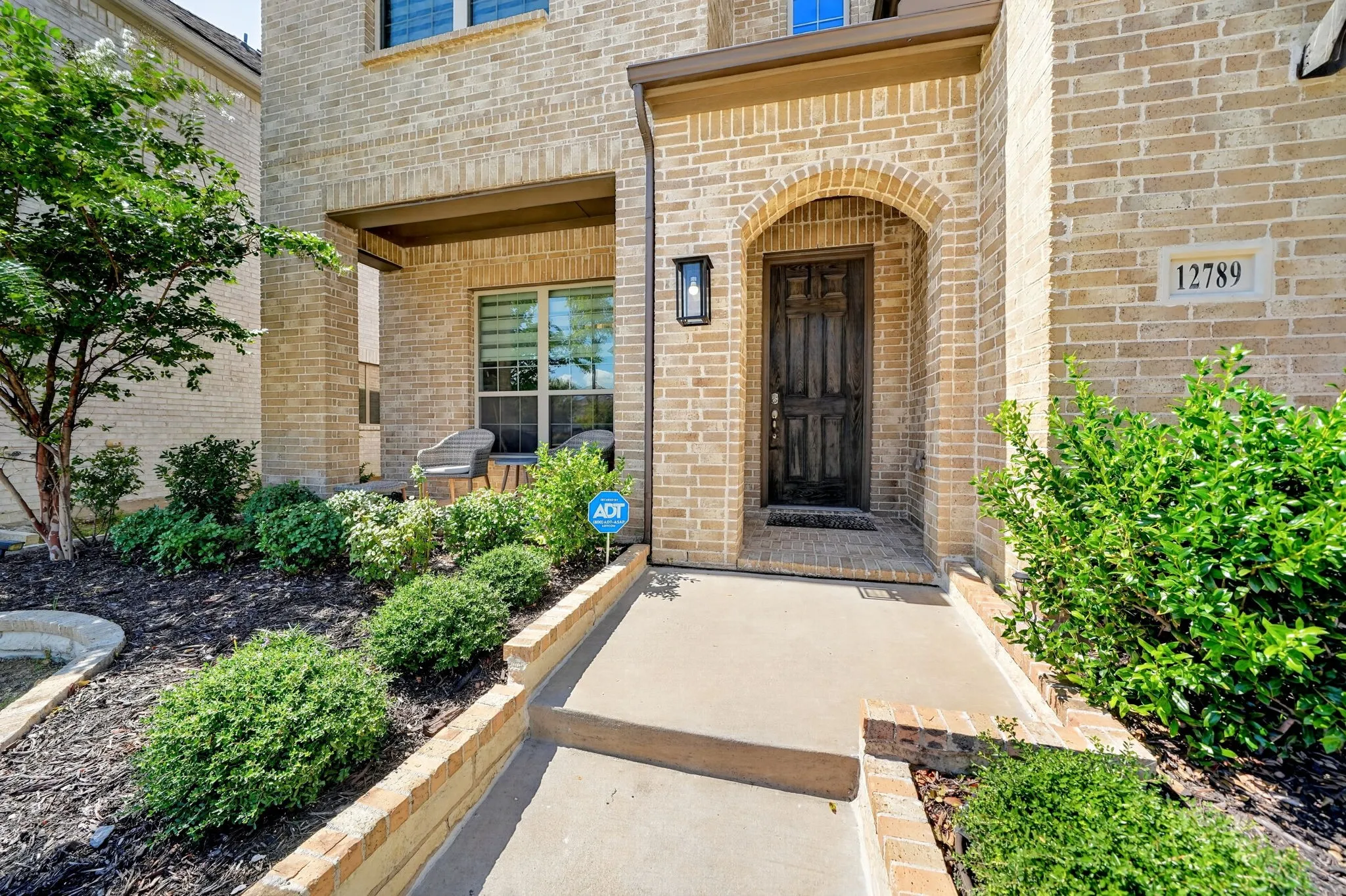 Brick exterior with an arched entry, dark wood-finish door, and integrated address plaque