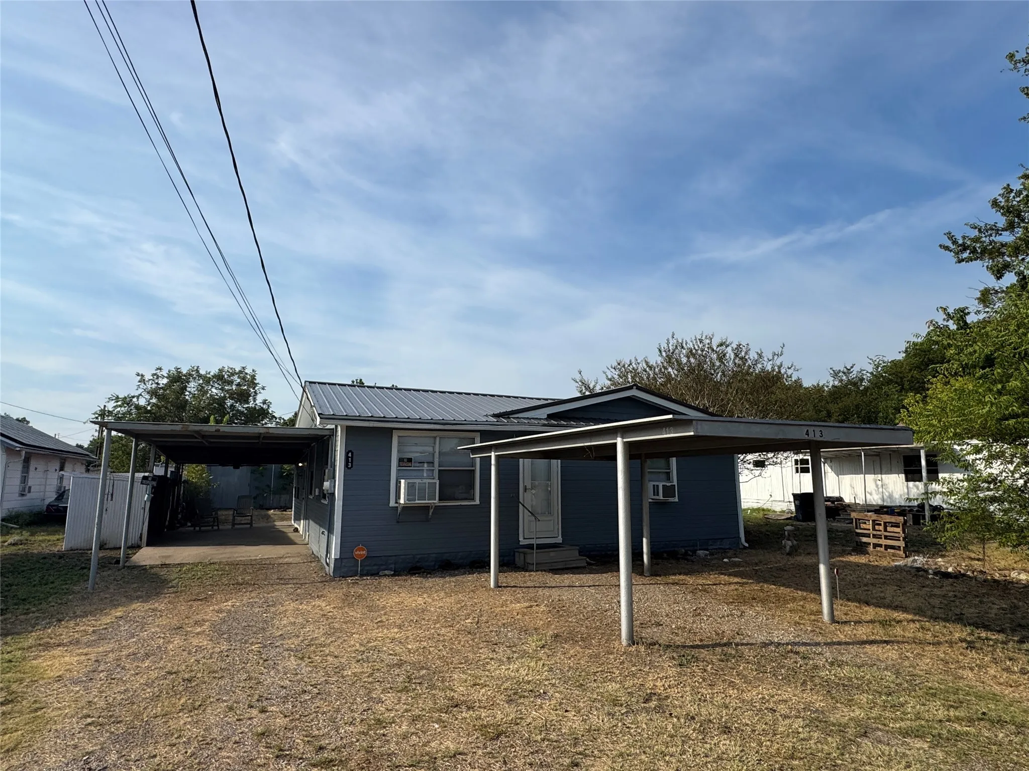 Blue exterior siding, metal roof, and two covered carports