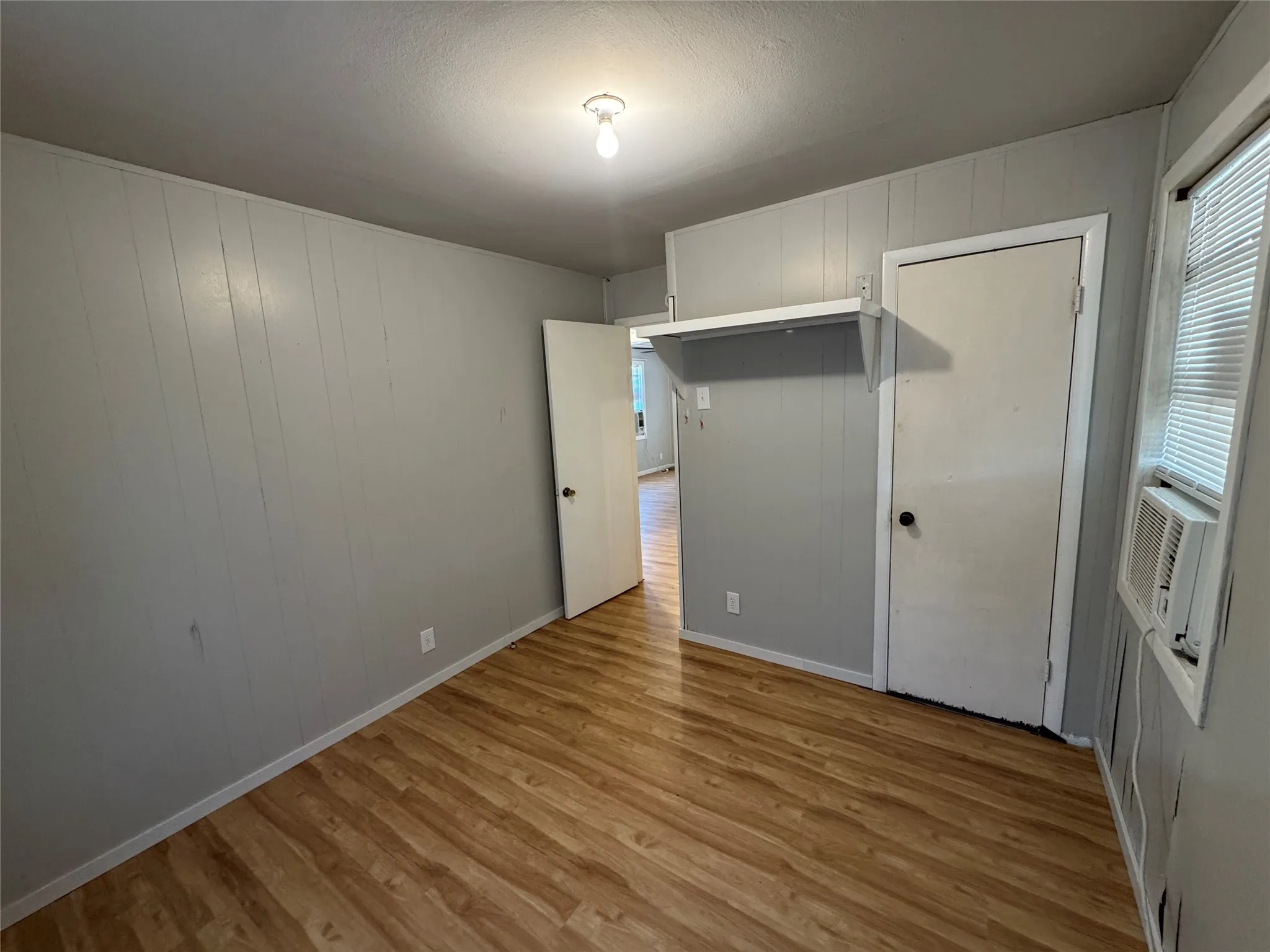 Wood-finish flooring, paneled wall finish, and a window with blinds