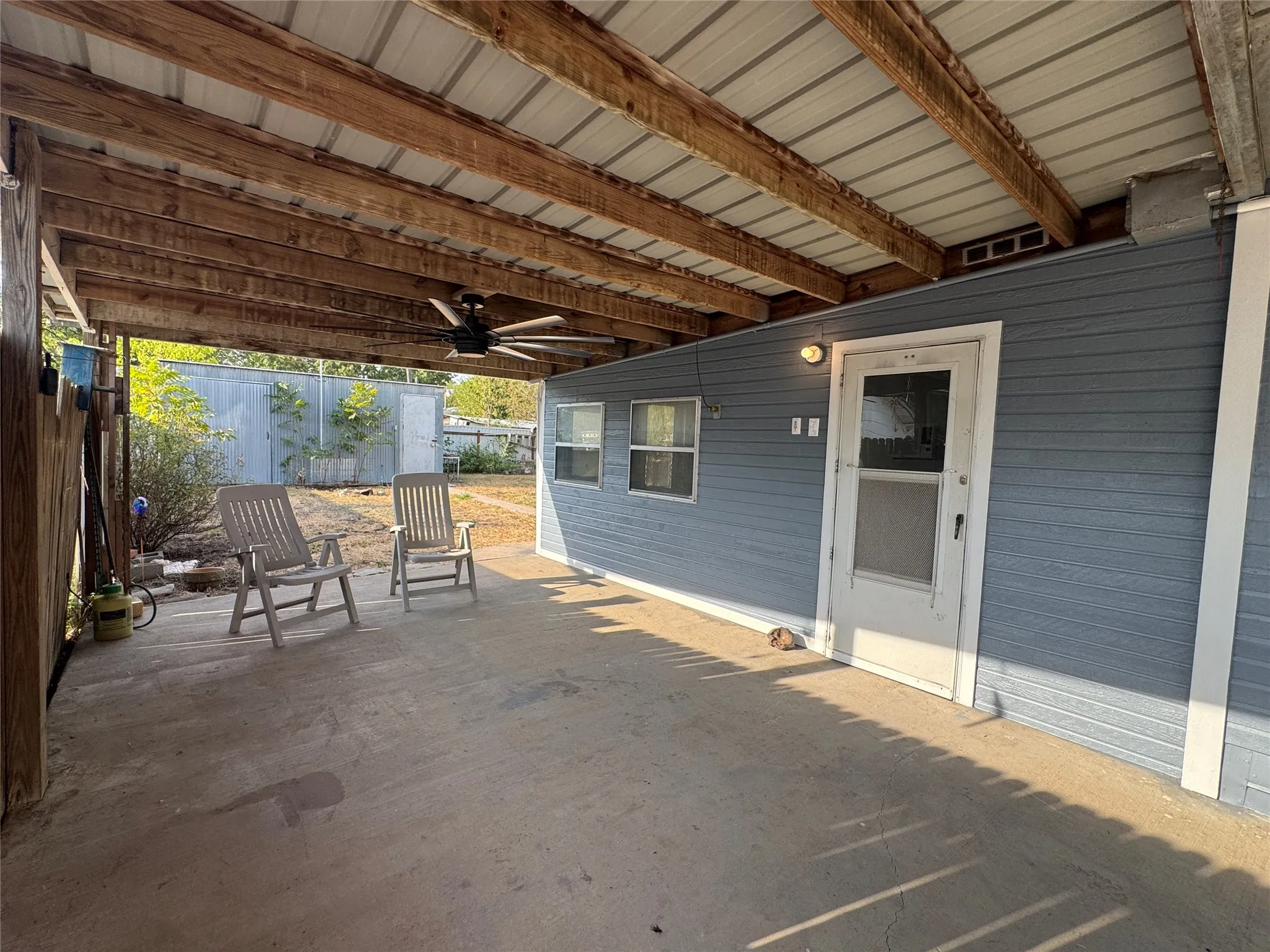 Covered patio with a concrete surface, exposed wood beam ceiling, metal roof, and a ceiling fan