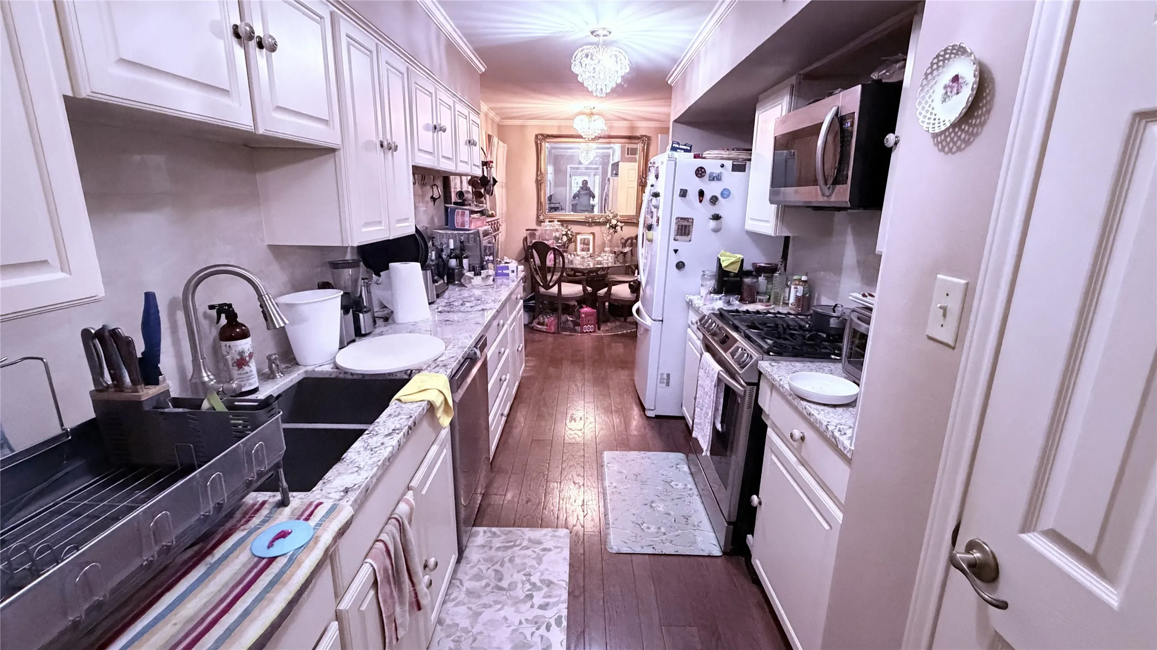 Galley kitchen featuring white cabinetry, light-toned countertops, and wood-finish flooring