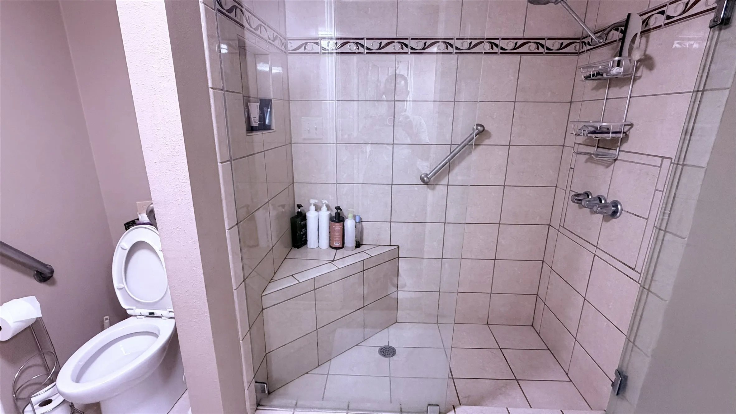 Walk-in shower with clear glass enclosure and tiled walls