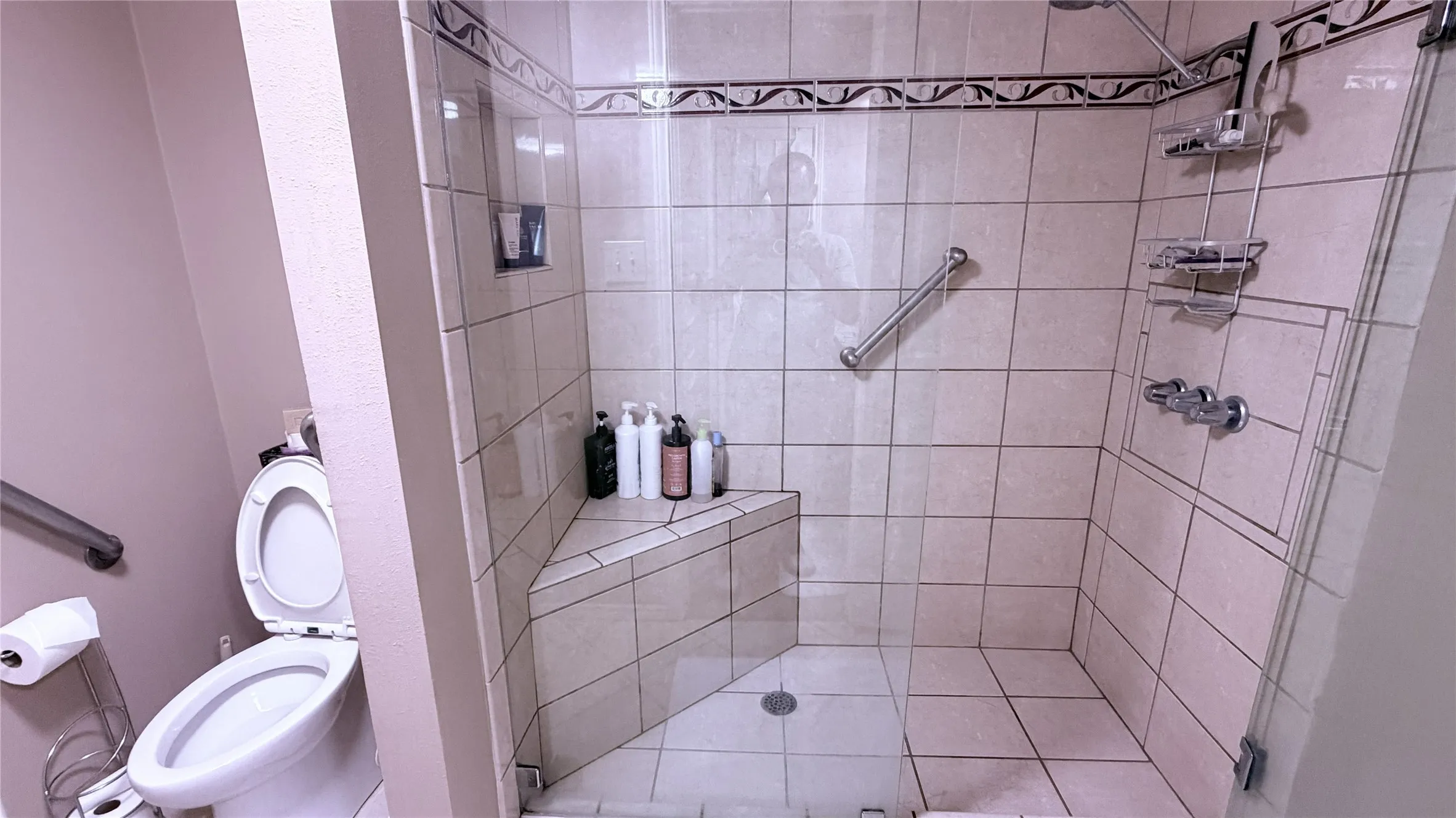 Tile-surround shower with a built-in bench, glass enclosure, and mounted grab bars