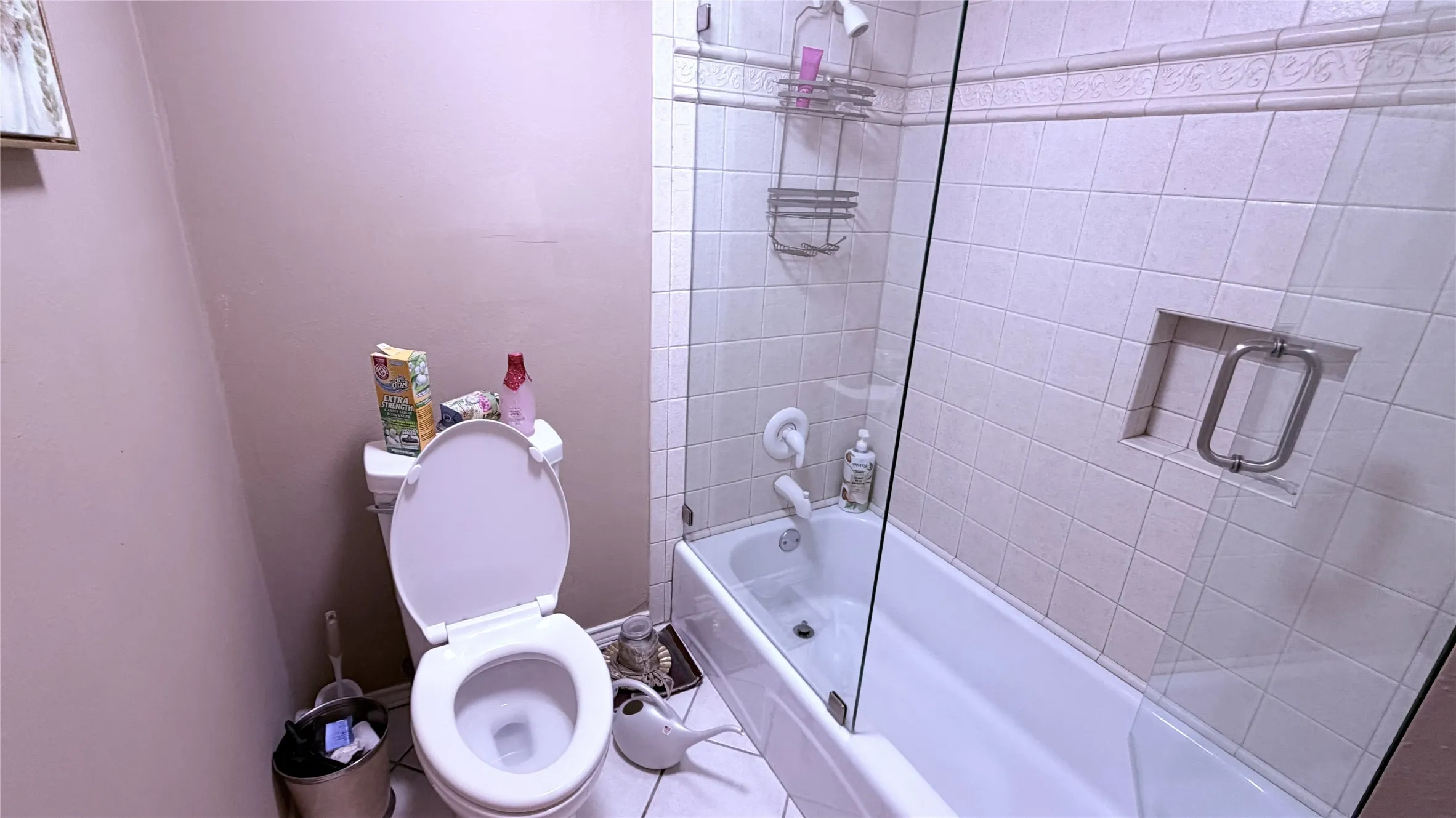 Built-in bathtub with a clear glass shower enclosure, white square-tiled wall surround, and a recessed shower niche