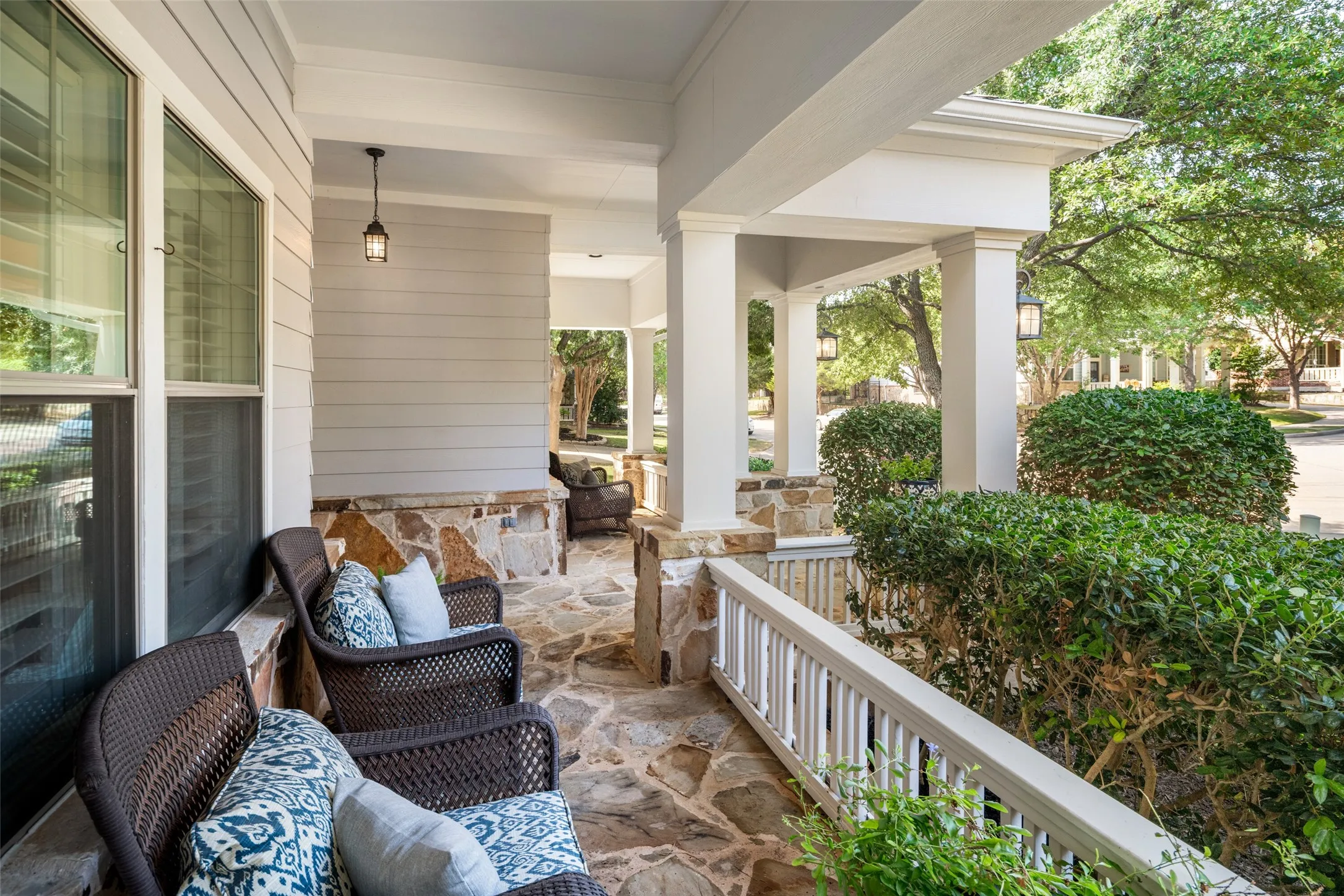 Flagstone Covered Front Porch Area surrounded by mature landscaping and beautiful trees providing shade.