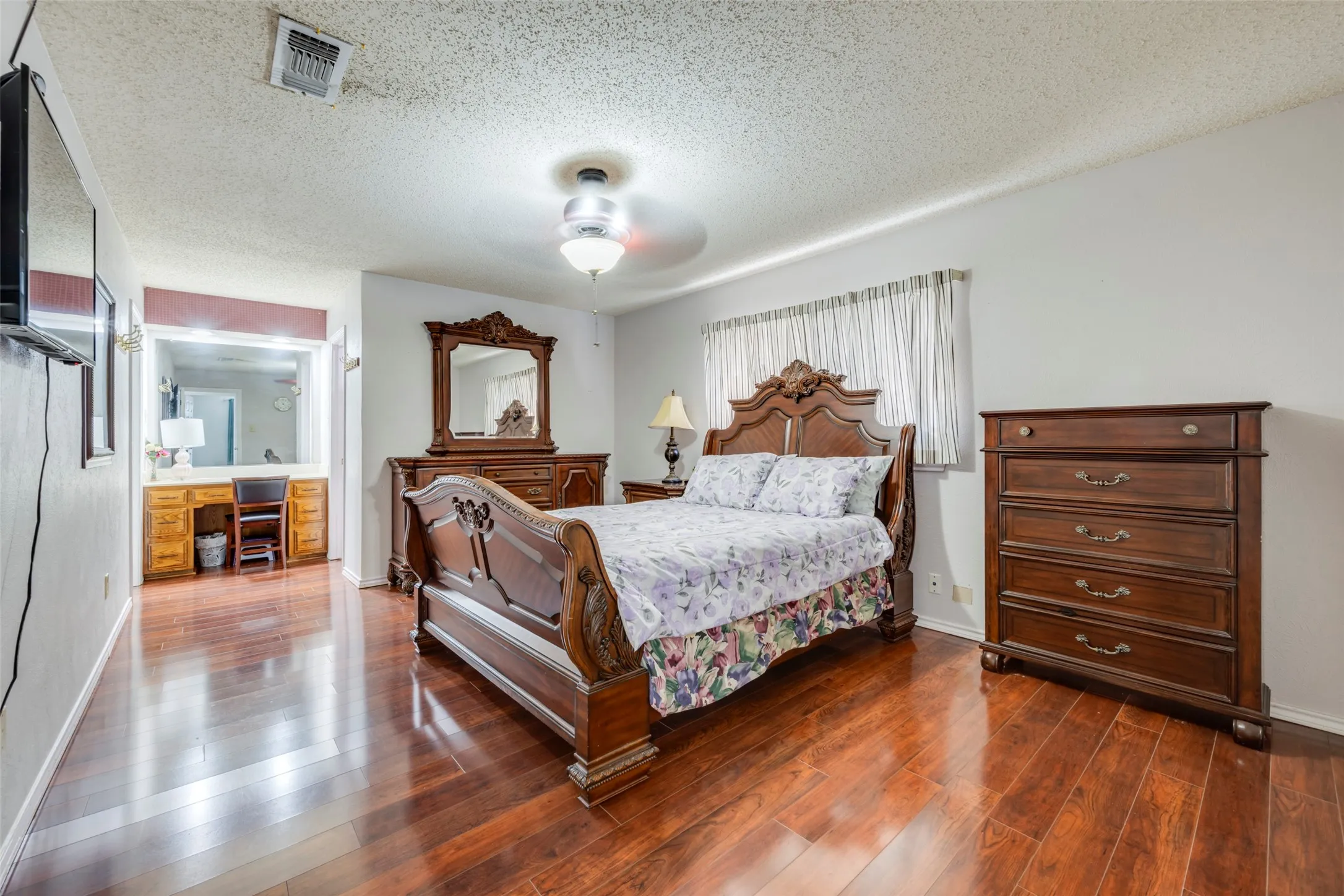 Hardwood-finish flooring, built-in vanity with wood cabinetry, ceiling fan with integrated lighting, and window with vertical blinds