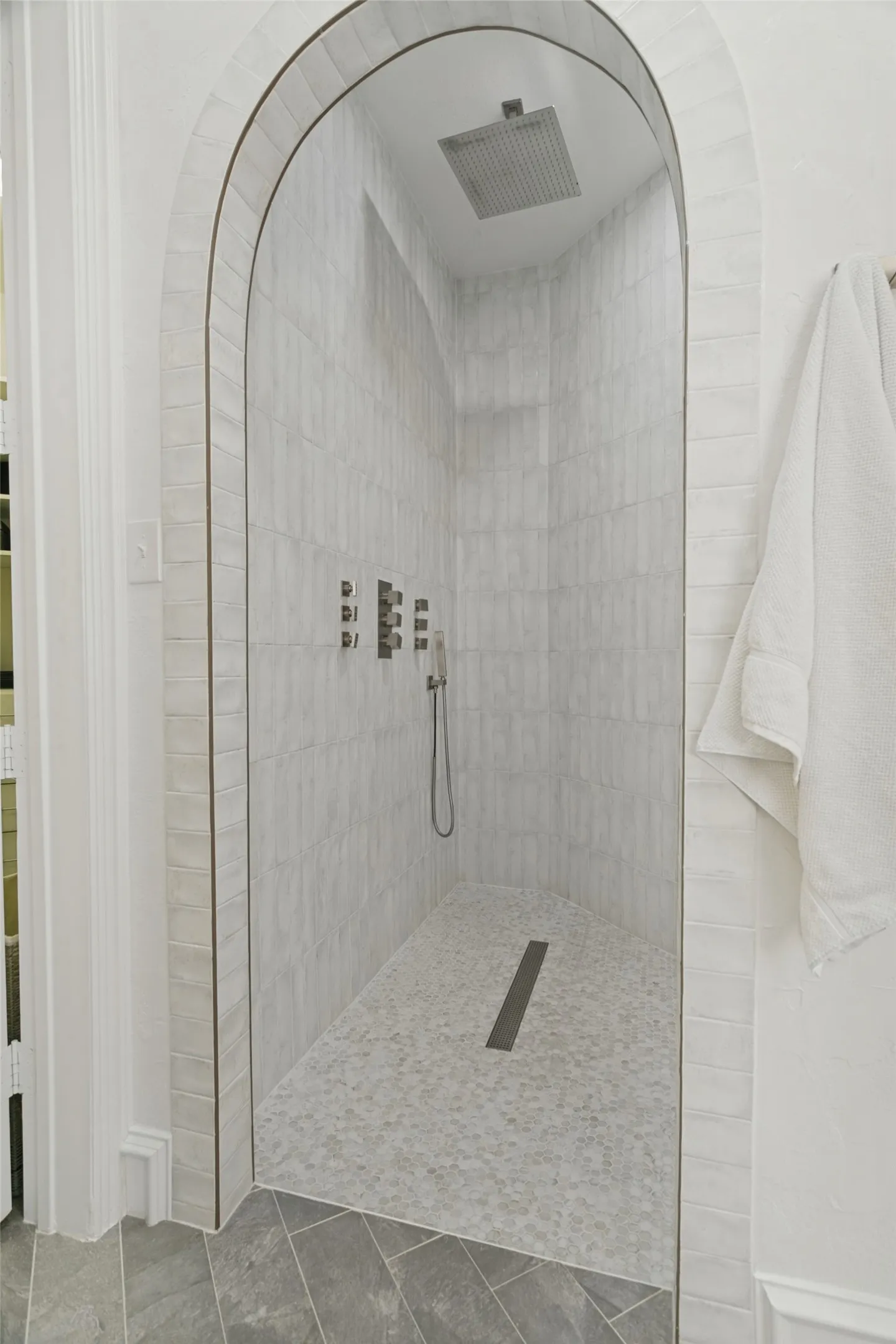 This walk-in shower features multiple shower heads and body sprays, as well as a bench and niche.