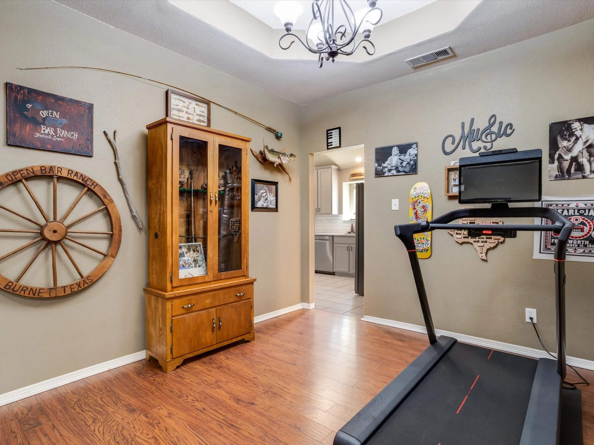Recessed ceiling with a central chandelier, wood-finish flooring, and light-toned wall paint