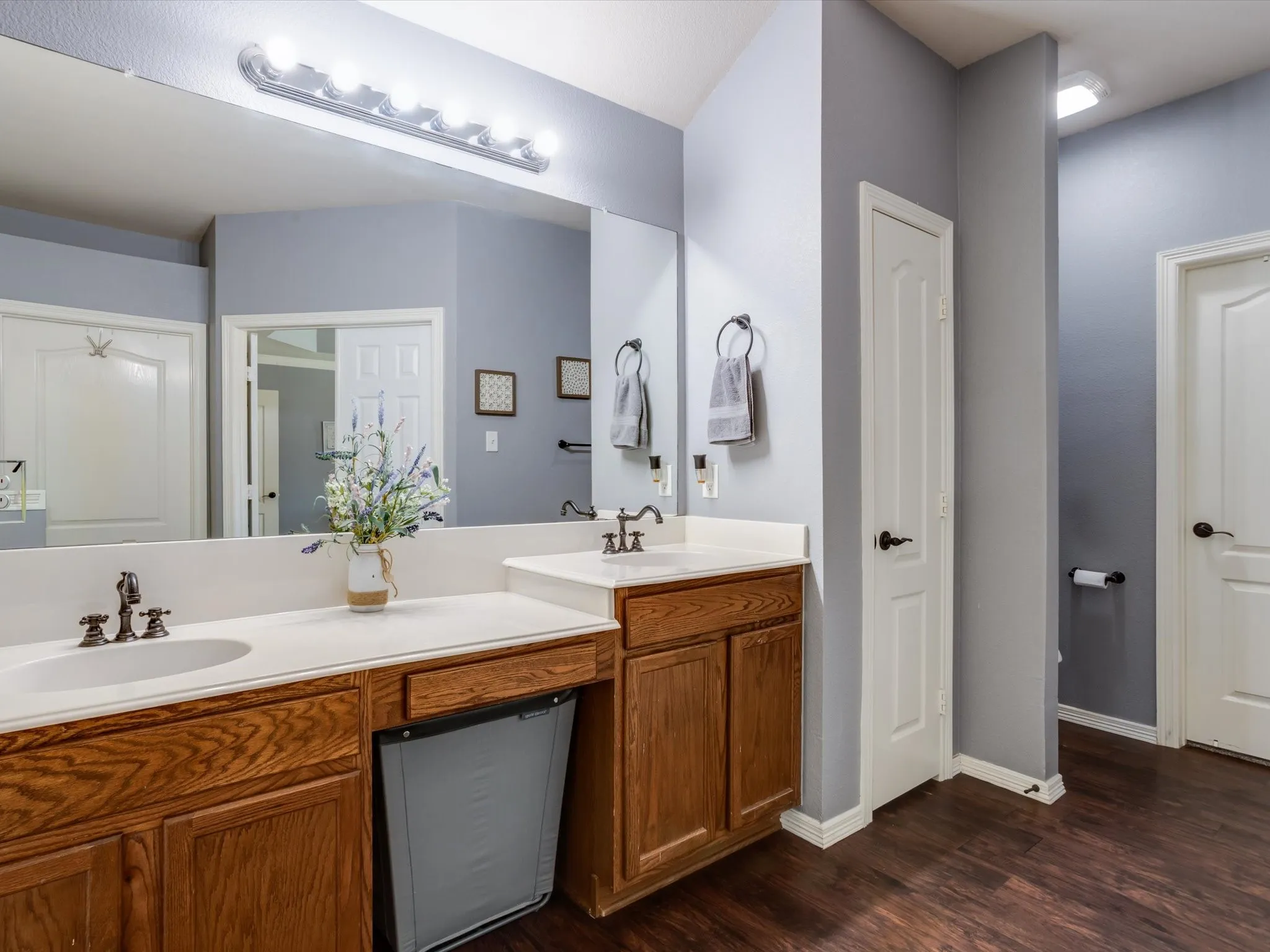 Dual vanity with integrated sinks, wood-finish cabinetry, and dark wood-finish flooring
