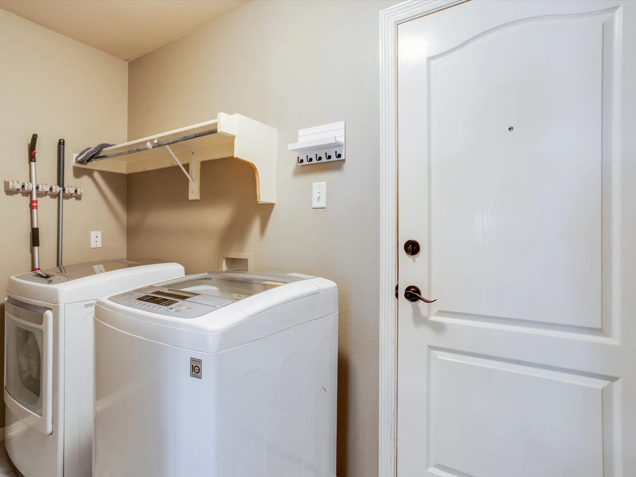 Laundry area featuring a built-in folding shelf, wall-mounted utility hooks, and a paneled interior door with dark hardware