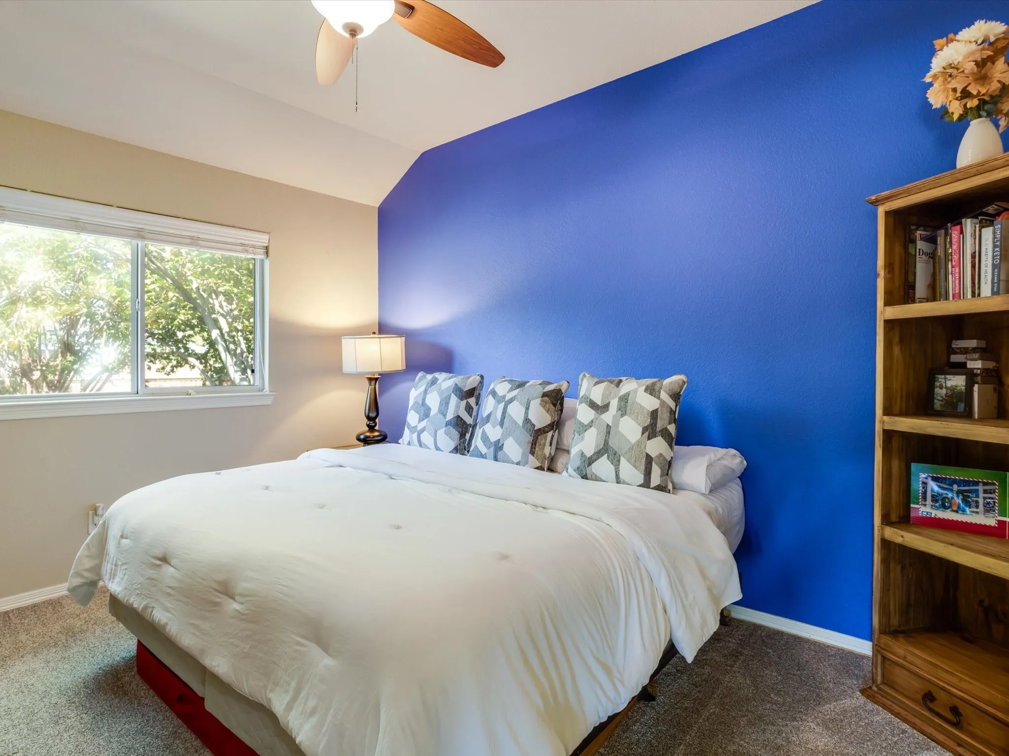 Angled ceiling featuring a ceiling fan, dual-pane window, and carpeted flooring