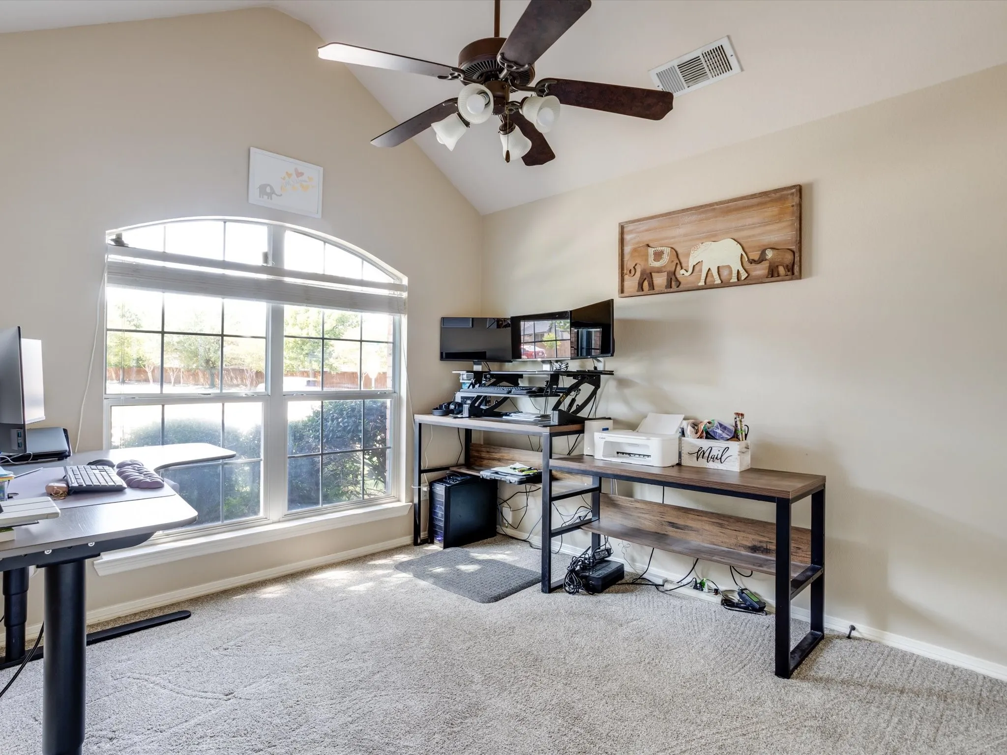Arched window with gridded panes, vaulted ceiling, ceiling fan with integrated lighting, and carpeted flooring