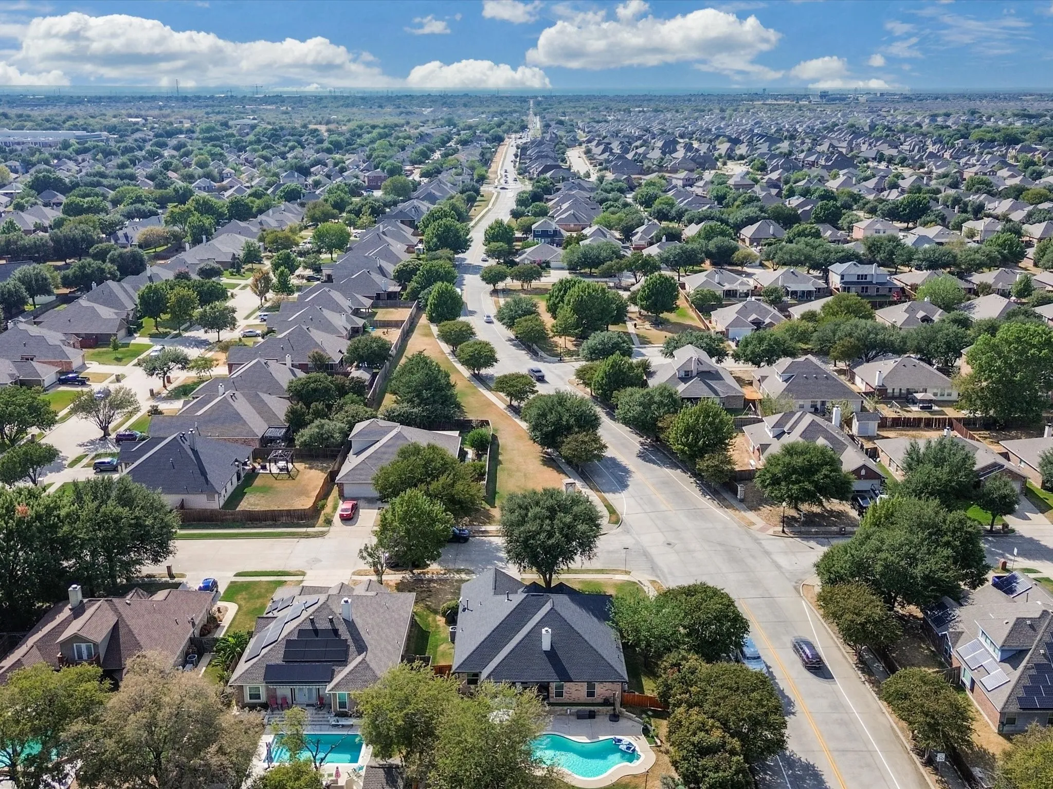 Residential community featuring a variety of single-family homes, mature trees, and paved roads