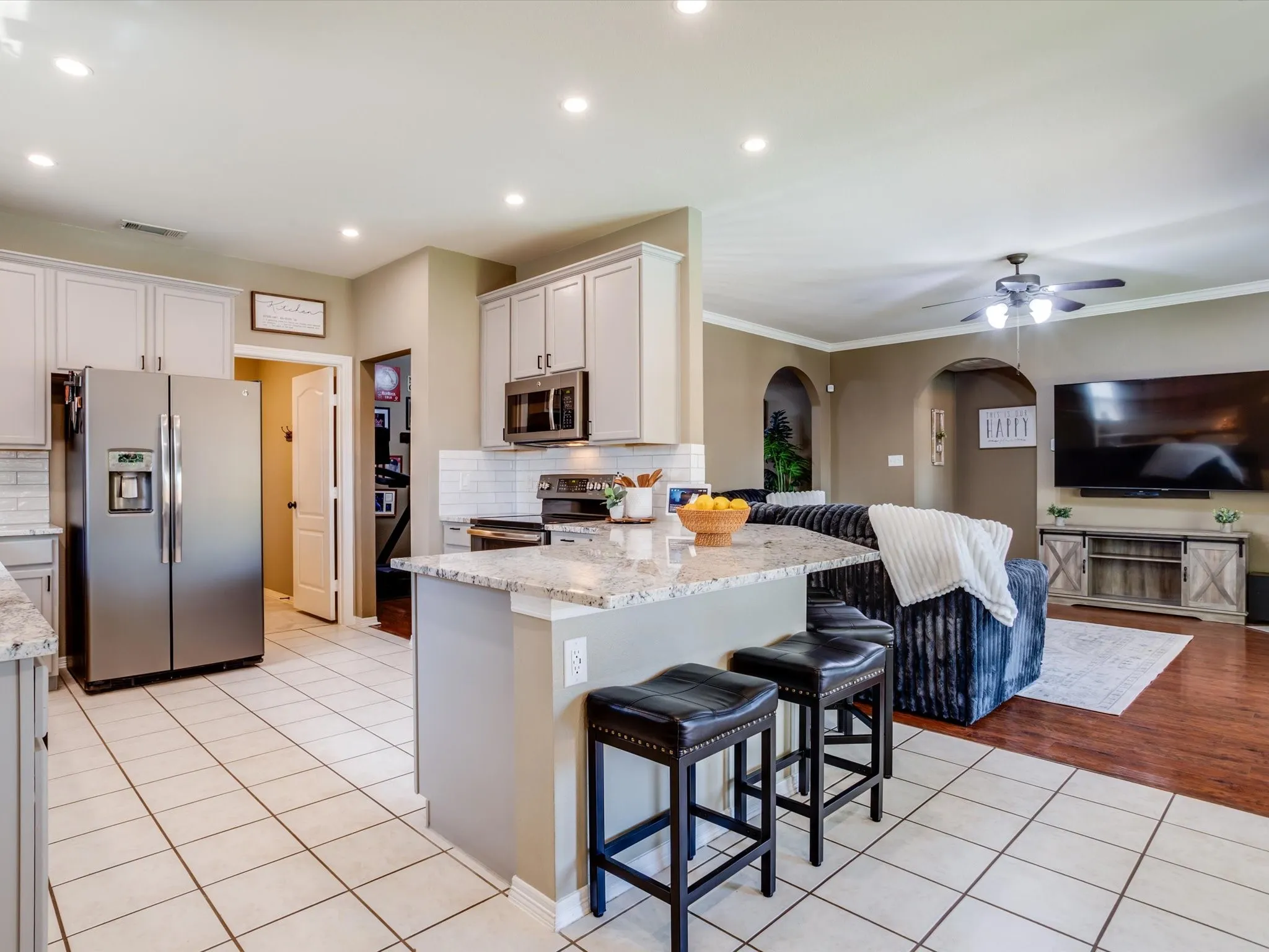 Kitchen with light-toned cabinetry, stainless steel appliances, and a granite-look countertop island