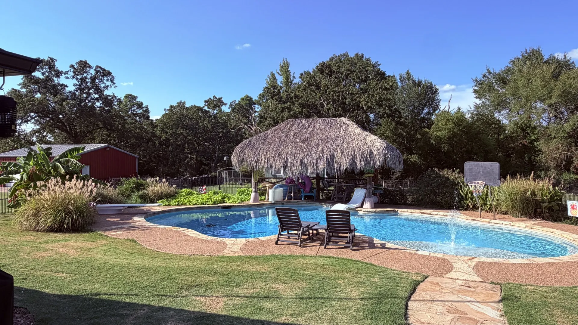 Free-form swimming pool with stone coping and a thatched-roof cabana