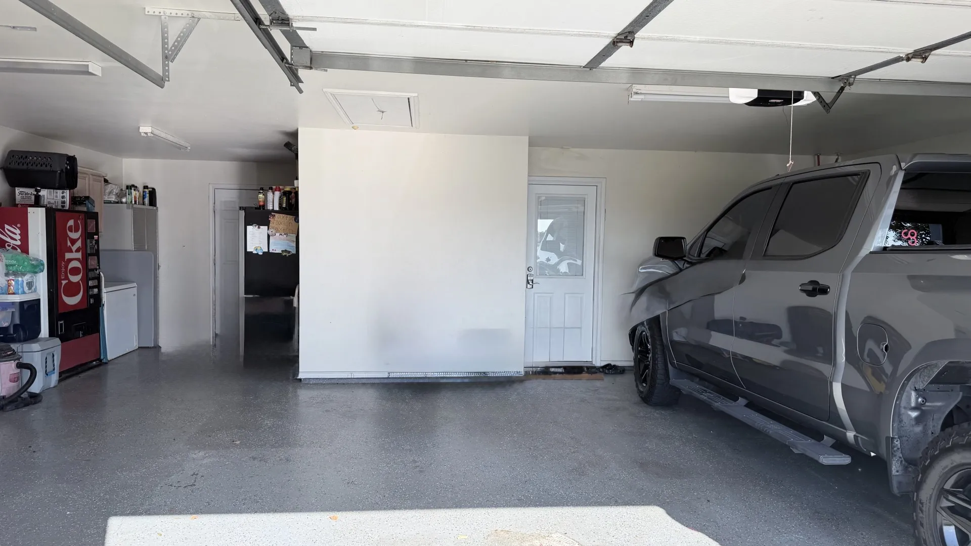 Concrete flooring with a speckled finish, white painted walls, and overhead fluorescent lighting