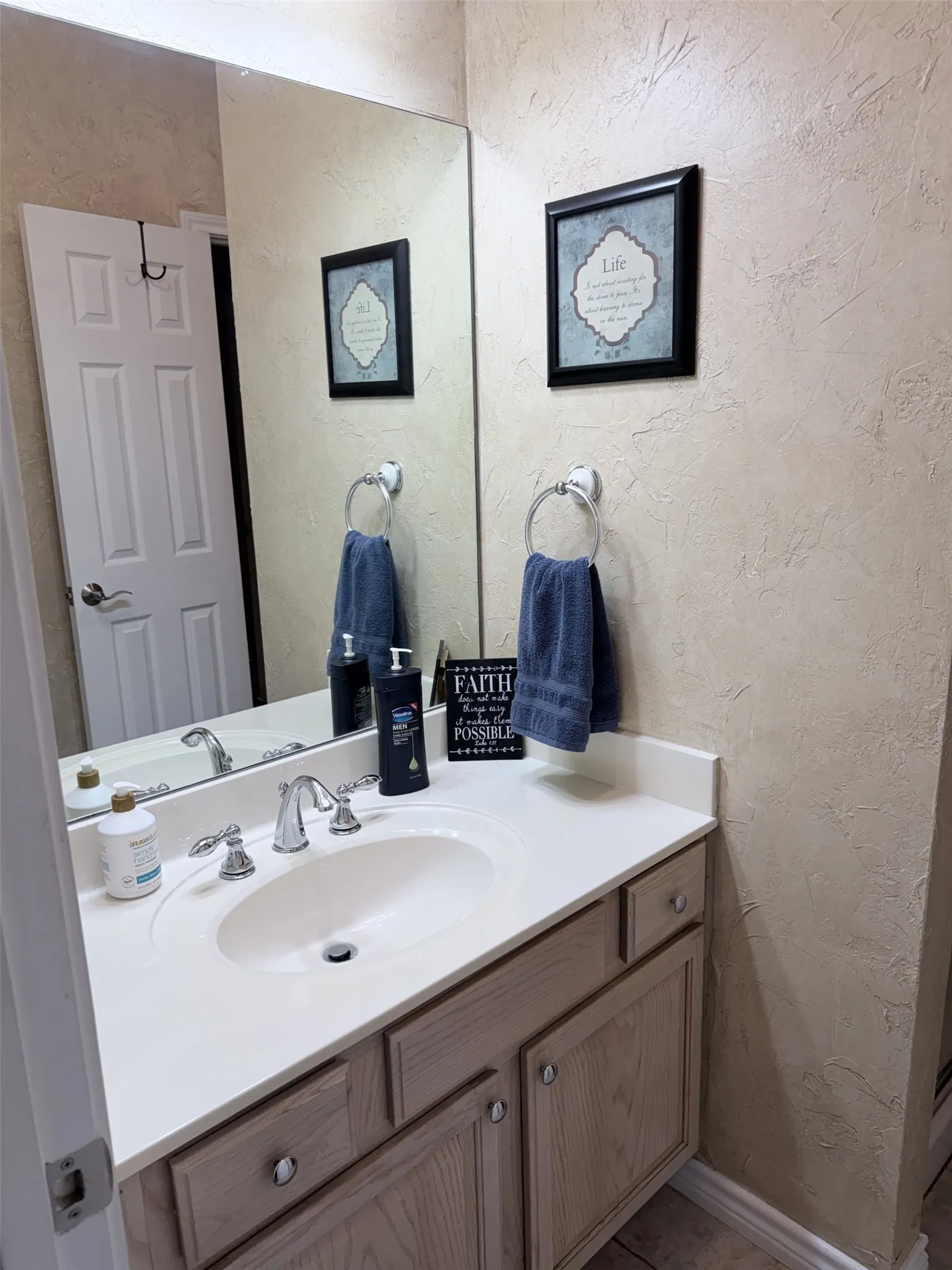 Vanity with an integrated sink, polished chrome faucet, and light wood-finish cabinetry