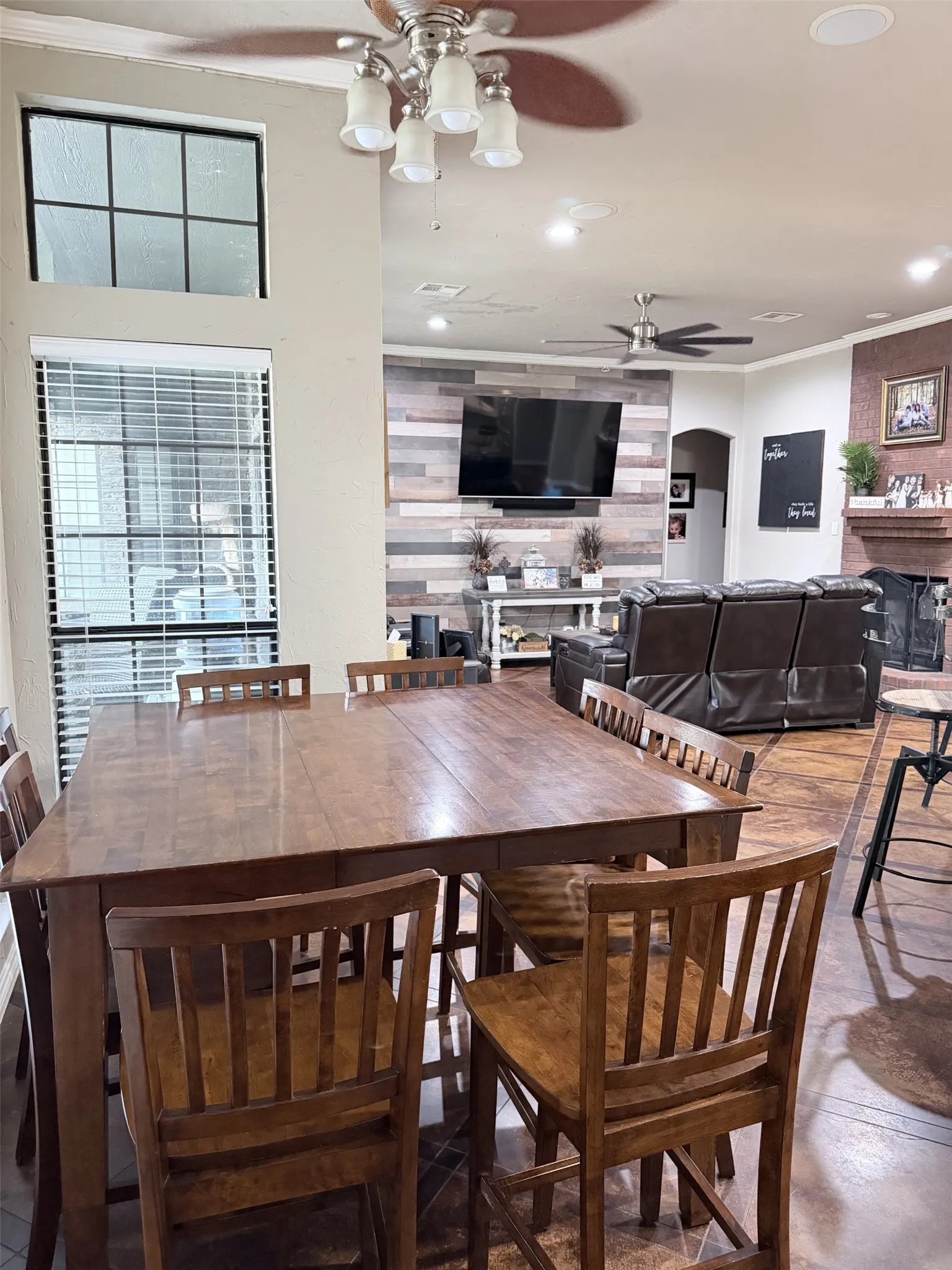 Open-concept space featuring a wood-finish flooring, a contemporary ceiling fan, and a rustic wood-plank accent wall