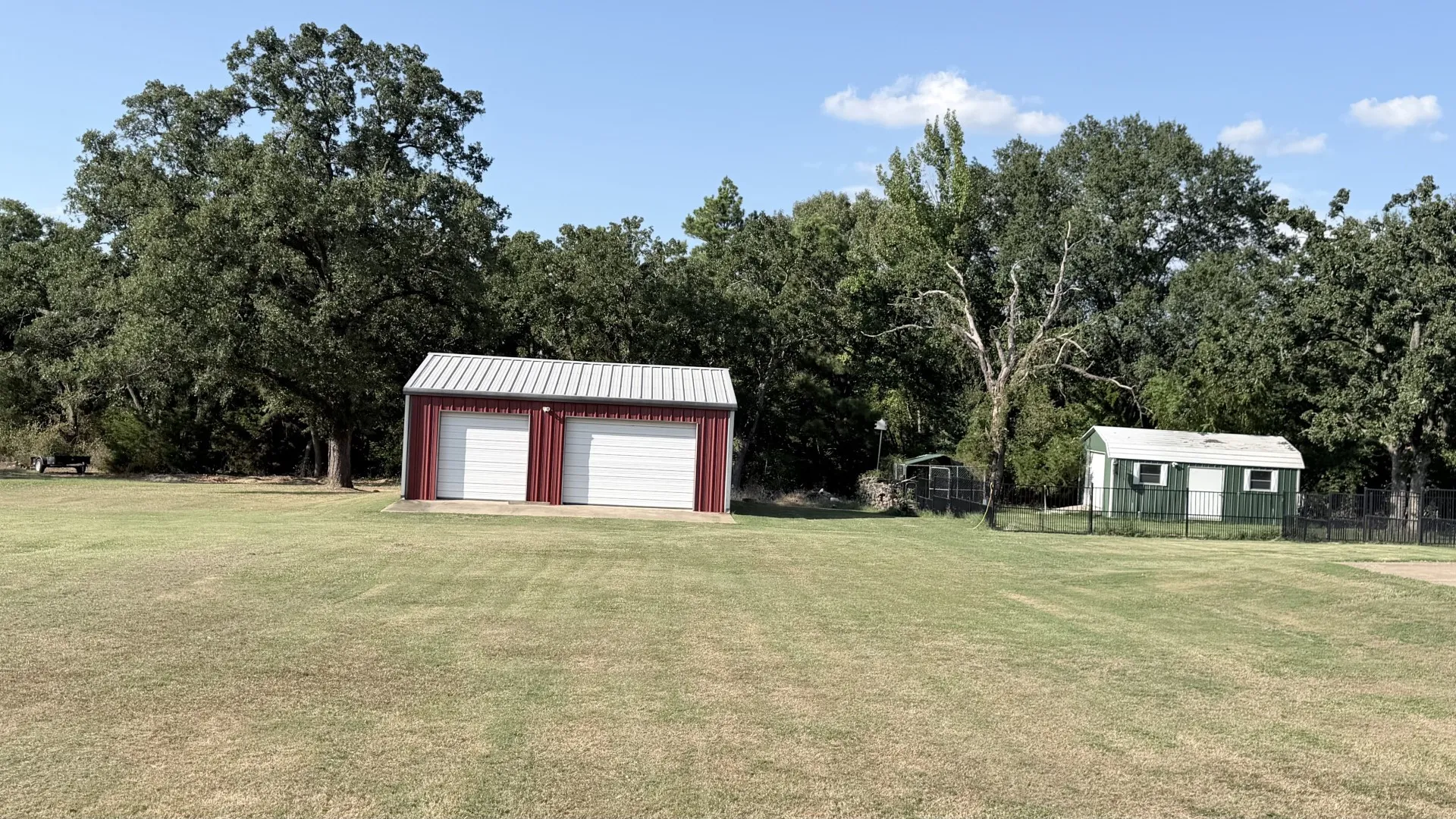 Two-bay red metal garage with white roll-up doors