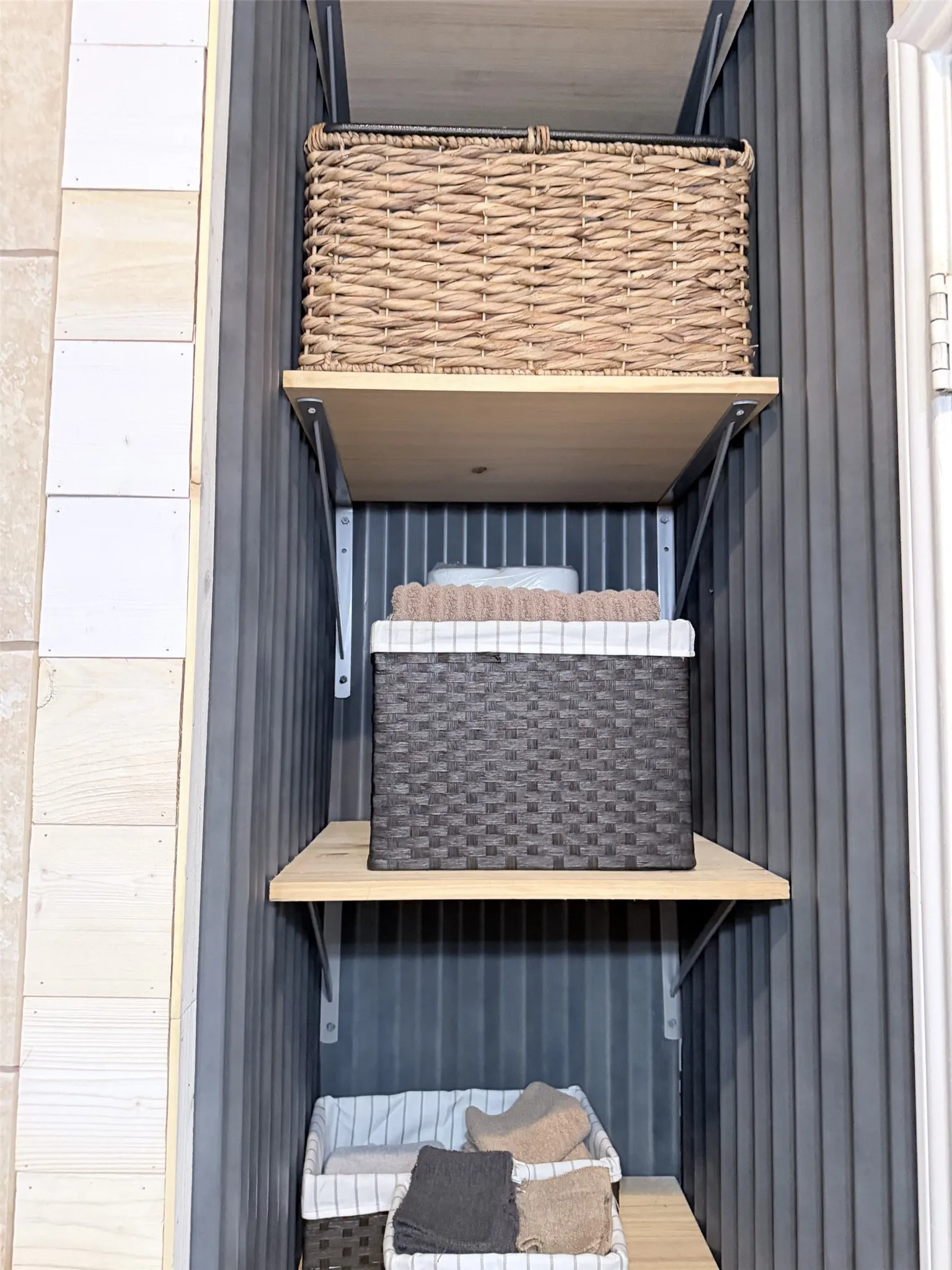 Built-in shelving with light wood-finish shelves and gray corrugated wall paneling