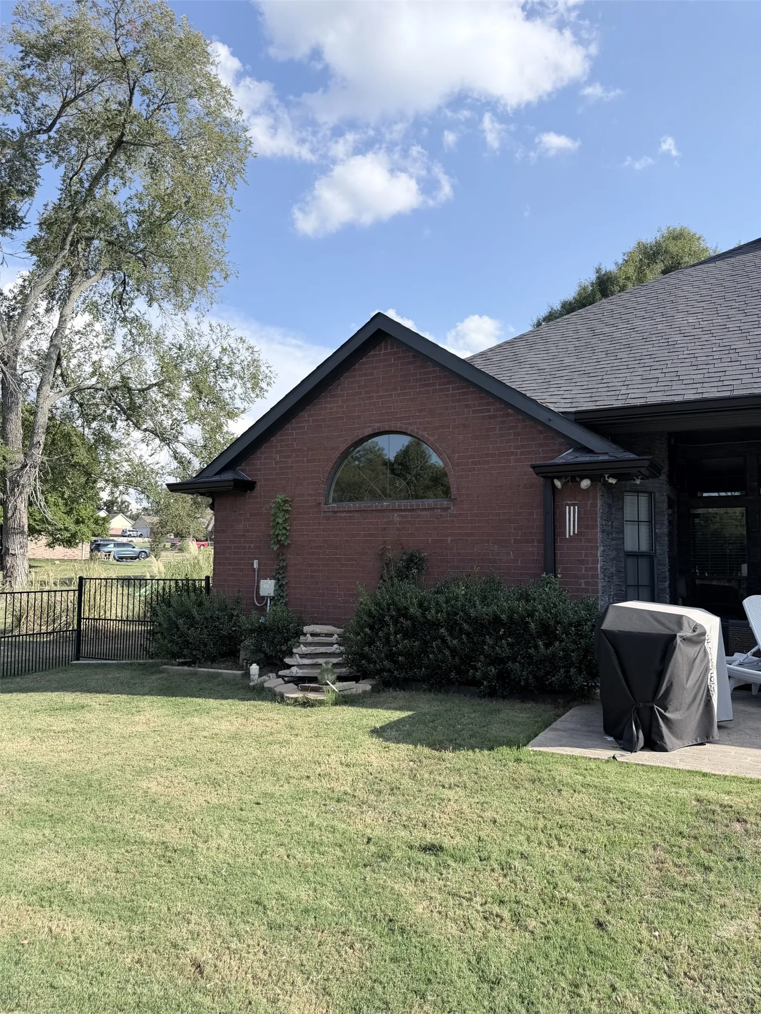 Brick exterior with a gabled roofline, semicircular window, and a stone water feature