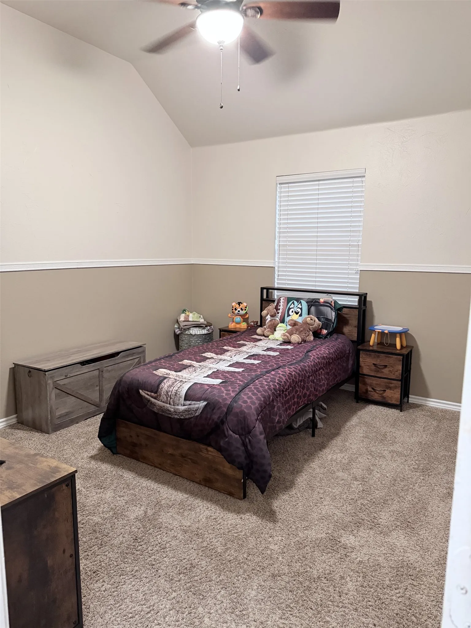 Vaulted ceiling with a ceiling fan, window with blinds, two-tone wall paint, and carpet flooring
