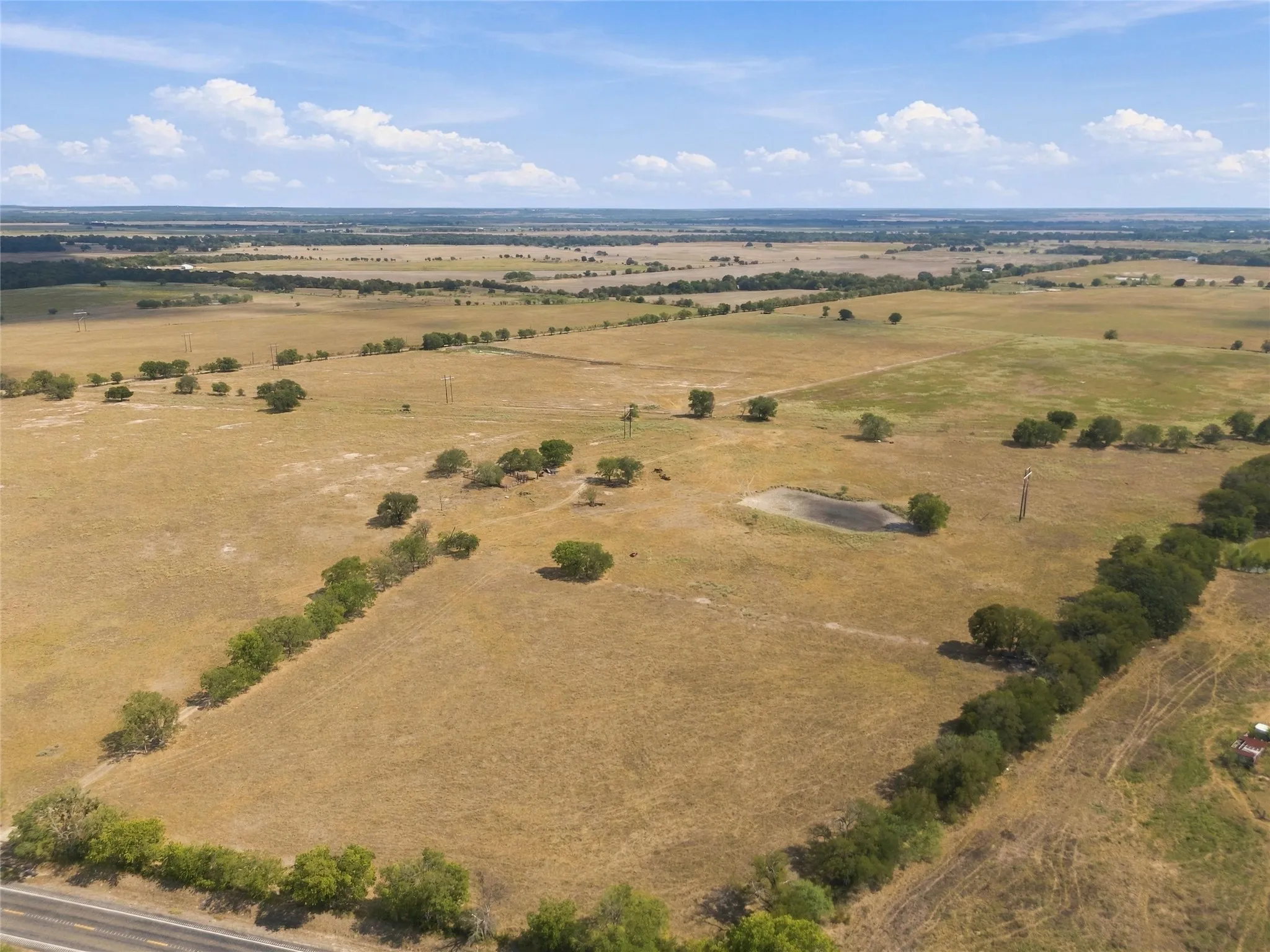 Expansive land parcel featuring a natural pond, mature trees, and a road frontage