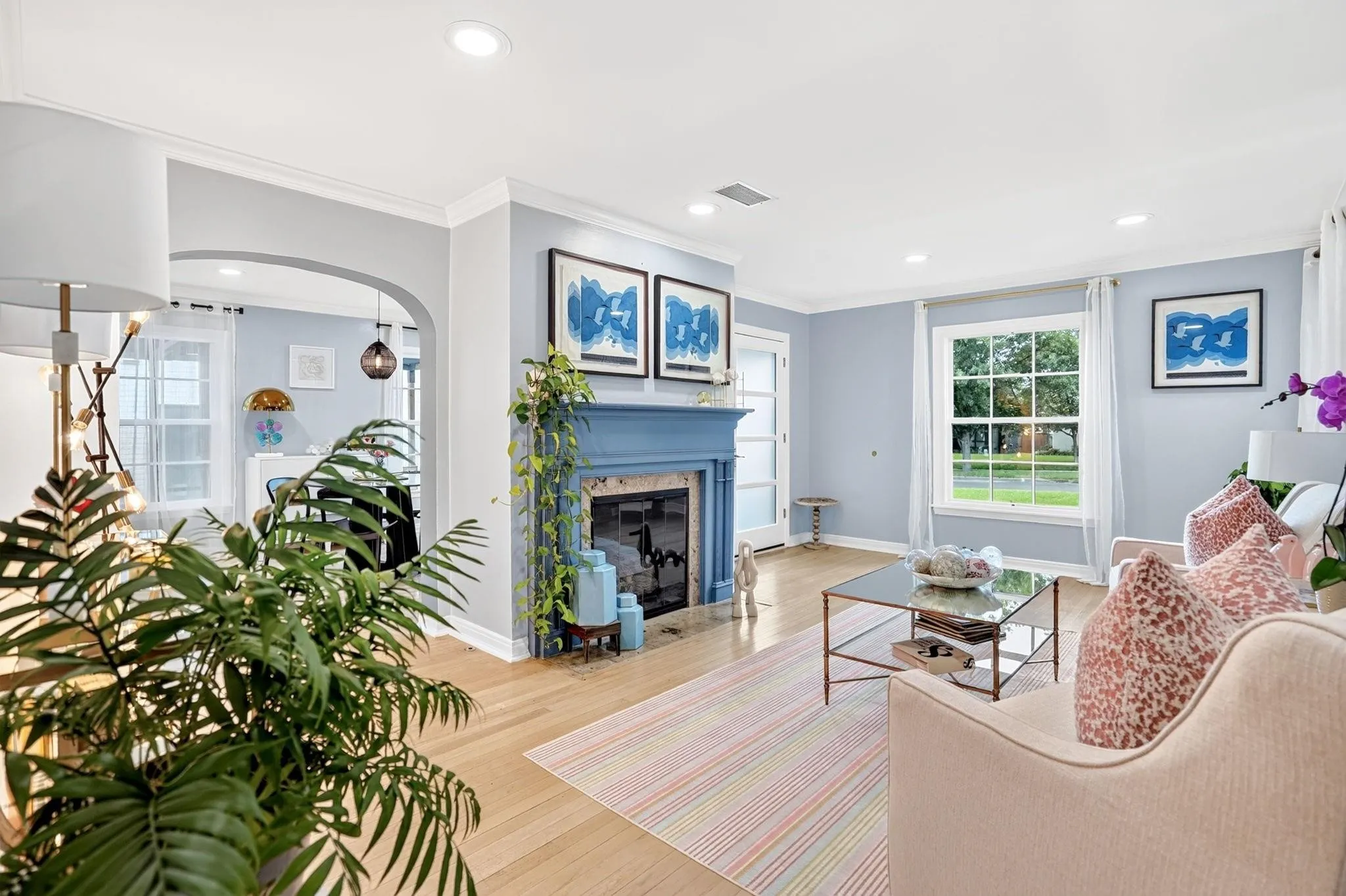 Hardwood flooring, arched doorway, fireplace with mantel, recessed lighting, and a multi-pane window