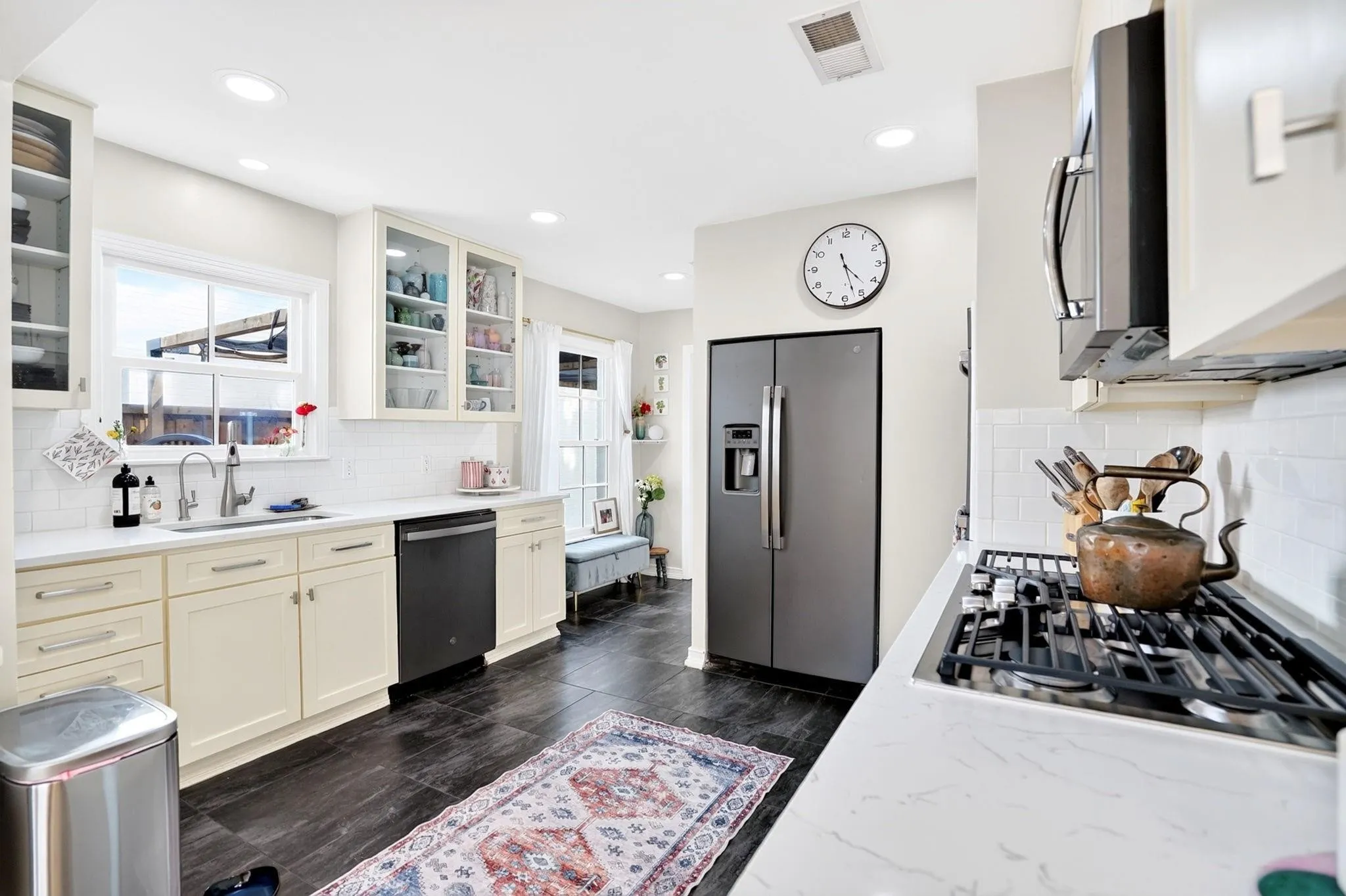 Modern kitchen featuring white cabinetry, white countertops, stainless steel appliances, dark tile flooring, and recessed lighting