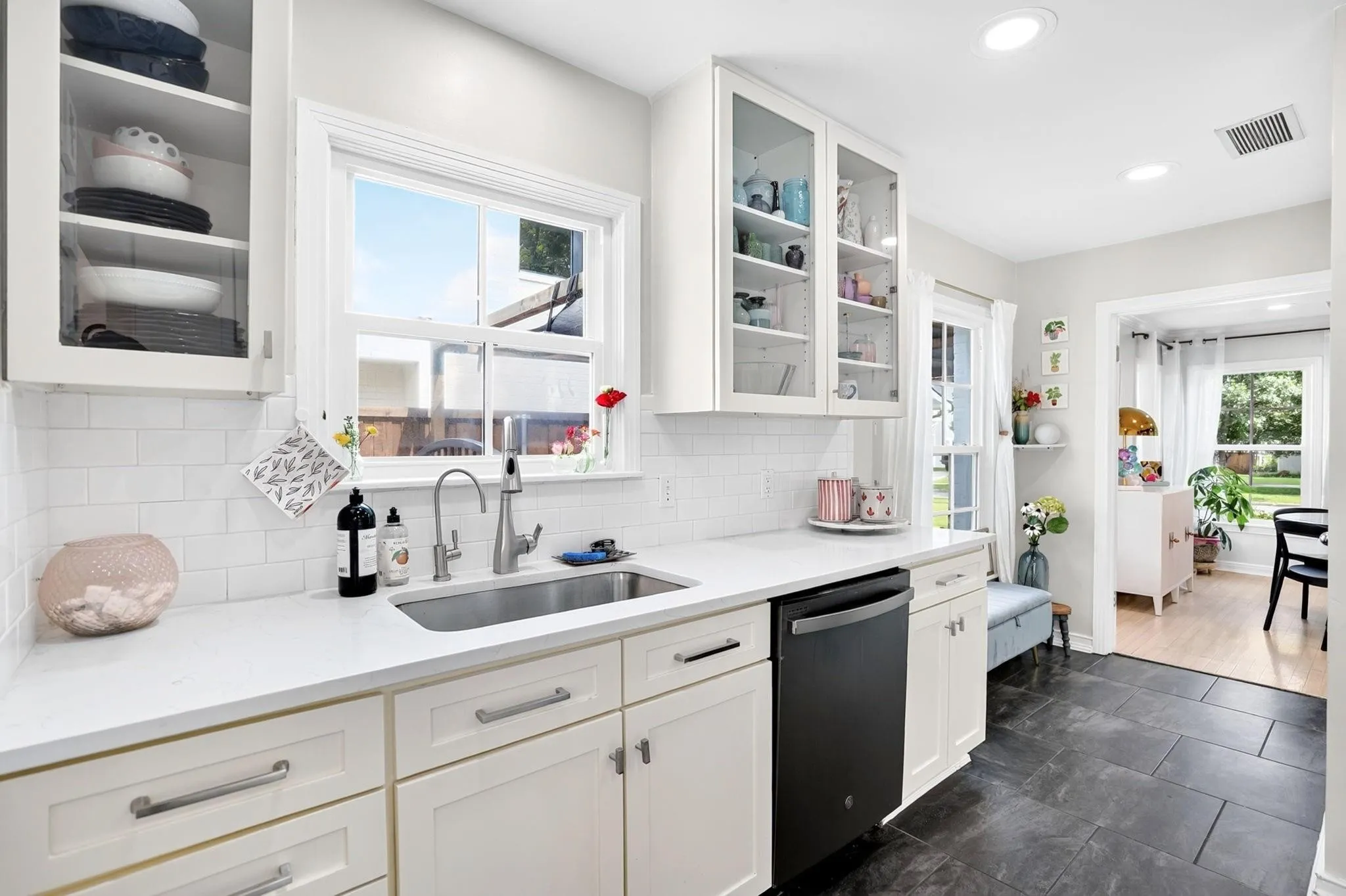 White shaker cabinetry, stainless steel sink, subway tile backsplash, white countertops, and dark floor tiles