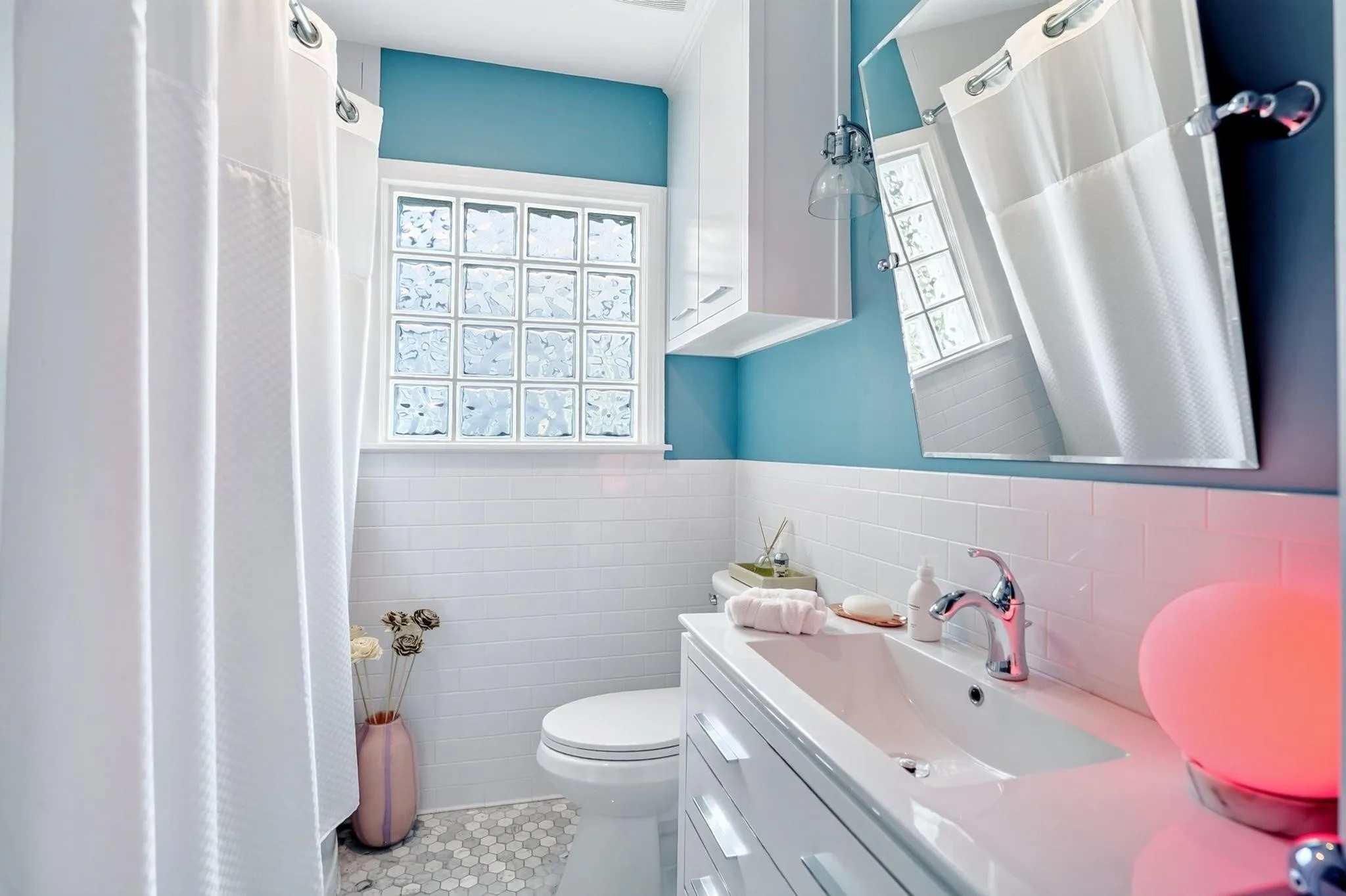Bathroom featuring a glass block window, white subway tile wainscoting, a hexagon tile floor, a built-in vanity with a rectangular basin, and a wall-mounted medicine cabinet