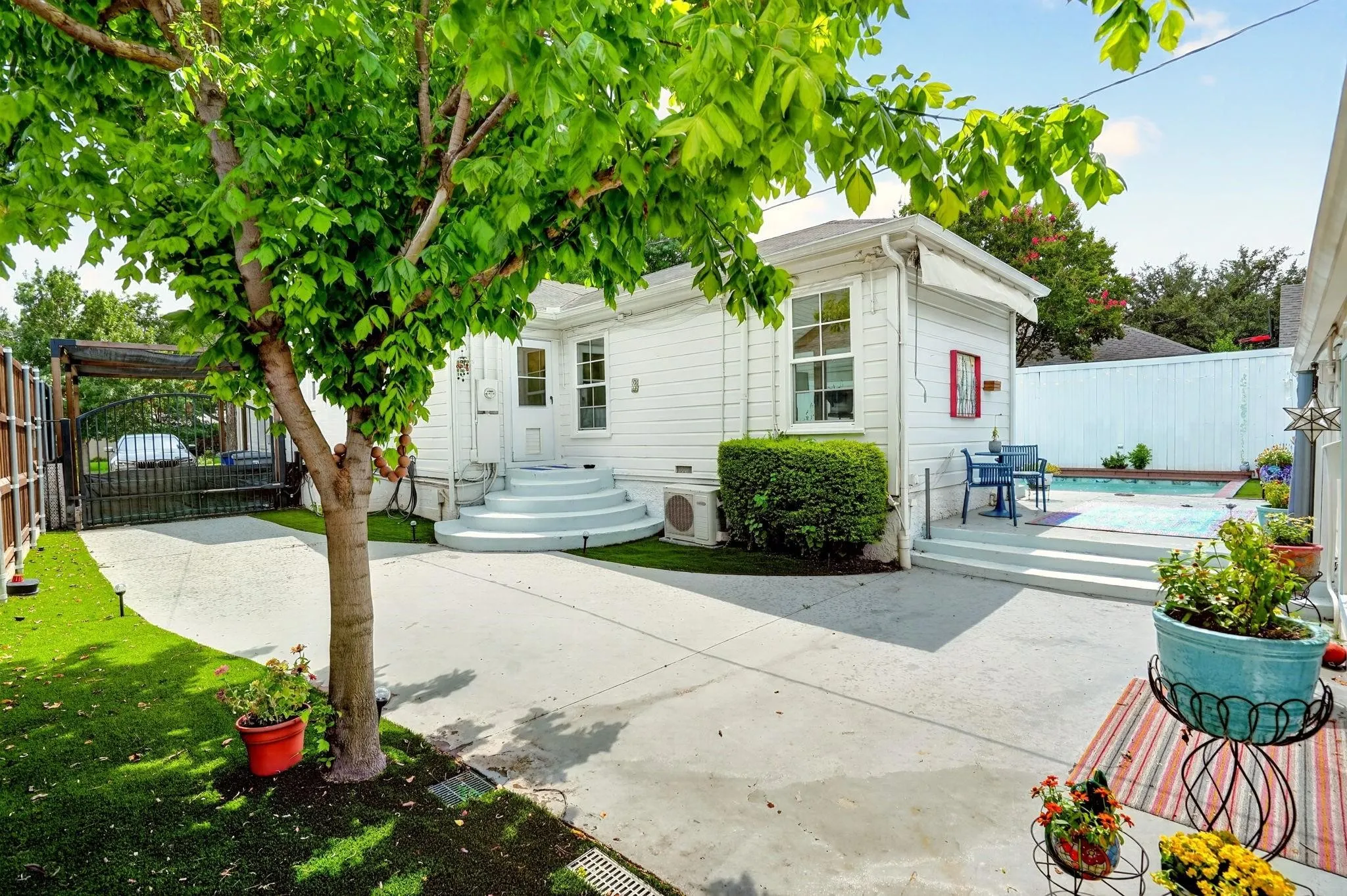 White exterior with a multi-tier entry, paved patio, and in-ground pool