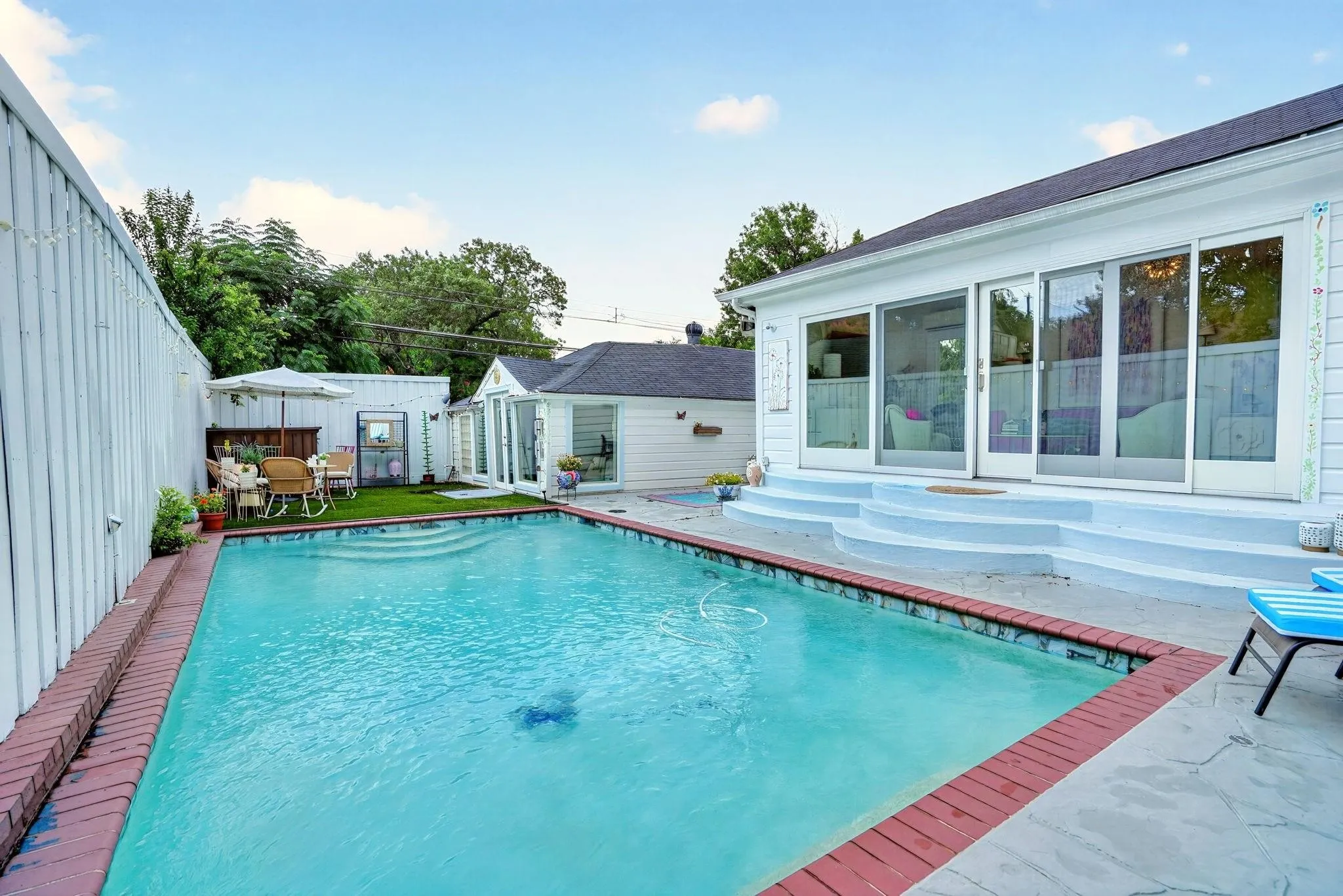 Swimming pool with brick coping, patio area, and a separate building