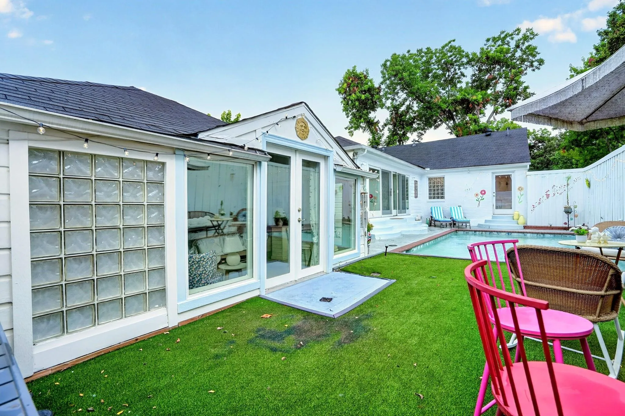Backyard featuring a rectangular pool, white privacy fencing, and a manicured lawn