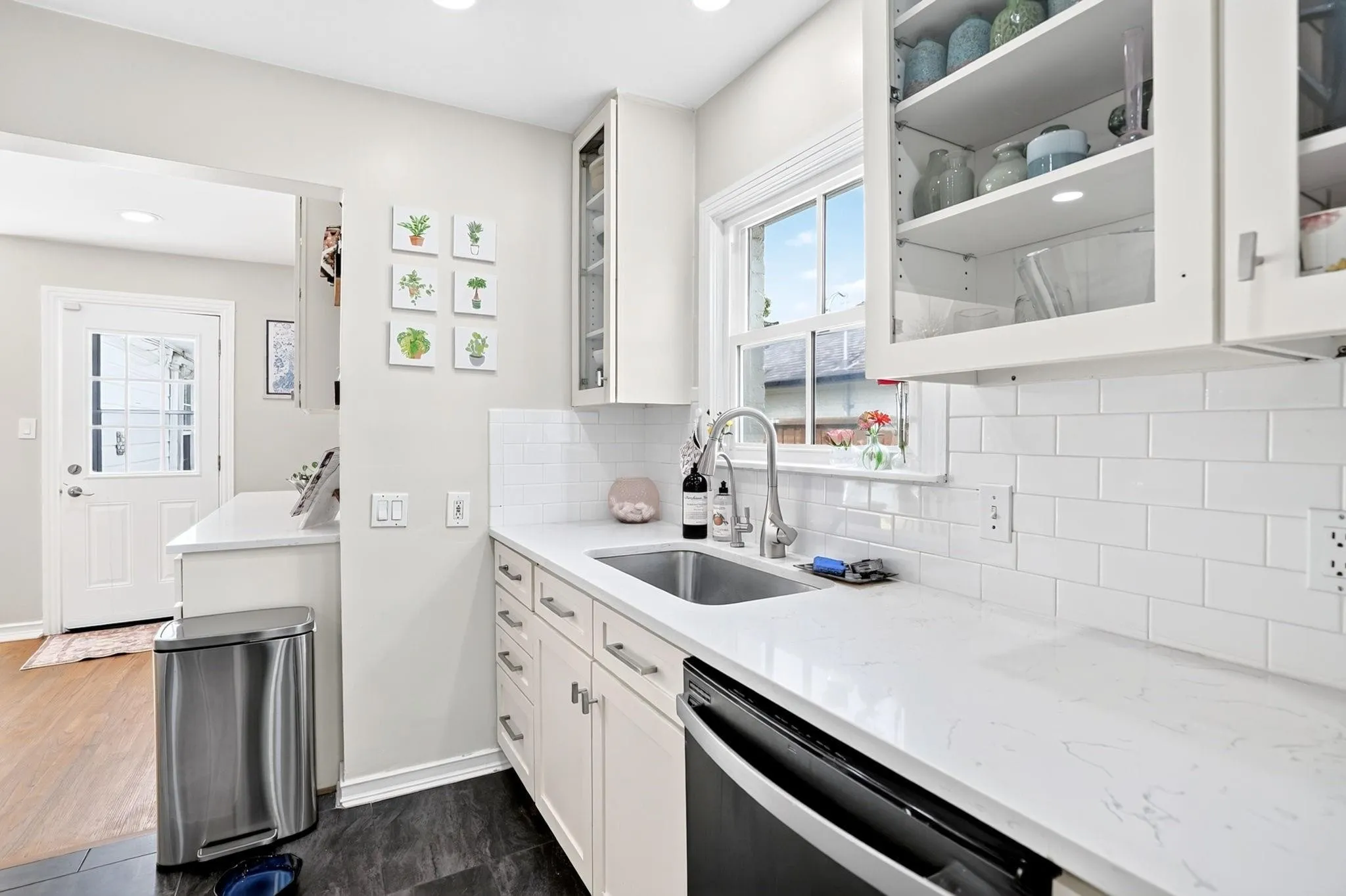 Kitchen featuring white cabinetry, white subway tile backsplash, a stainless steel sink, and light-toned countertops