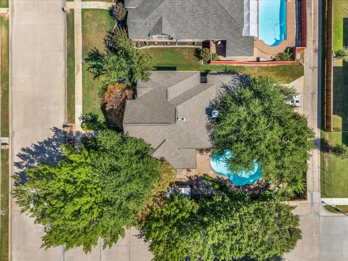 Property featuring a swimming pool, mature trees, and a shingle roof