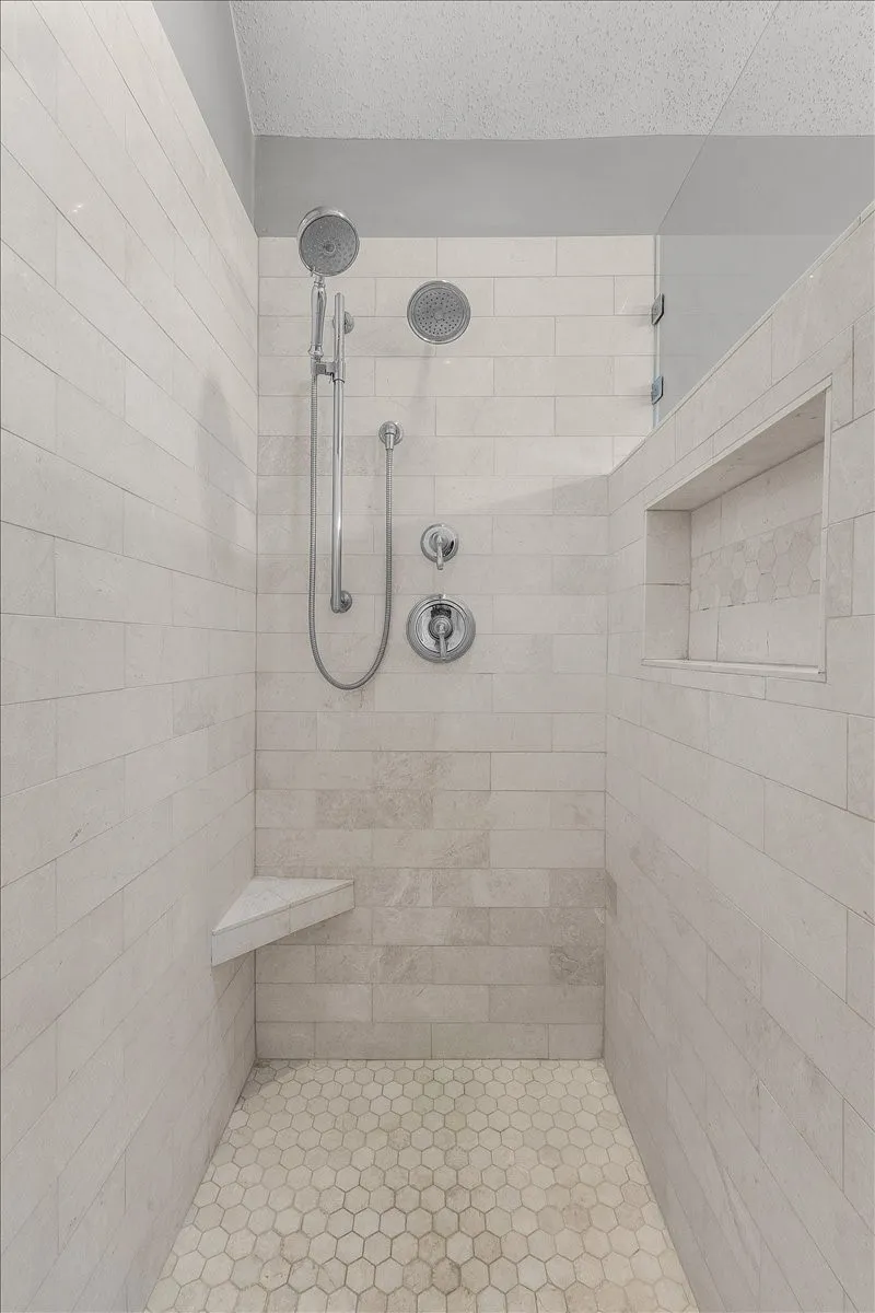 Tiled shower enclosure featuring a corner bench, recessed niche, and dual shower heads