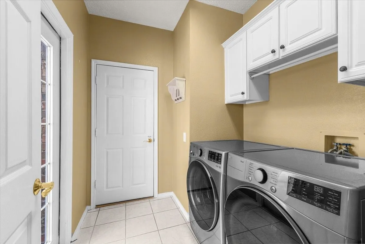 Laundry area featuring white cabinetry, tile flooring, and a solid white door