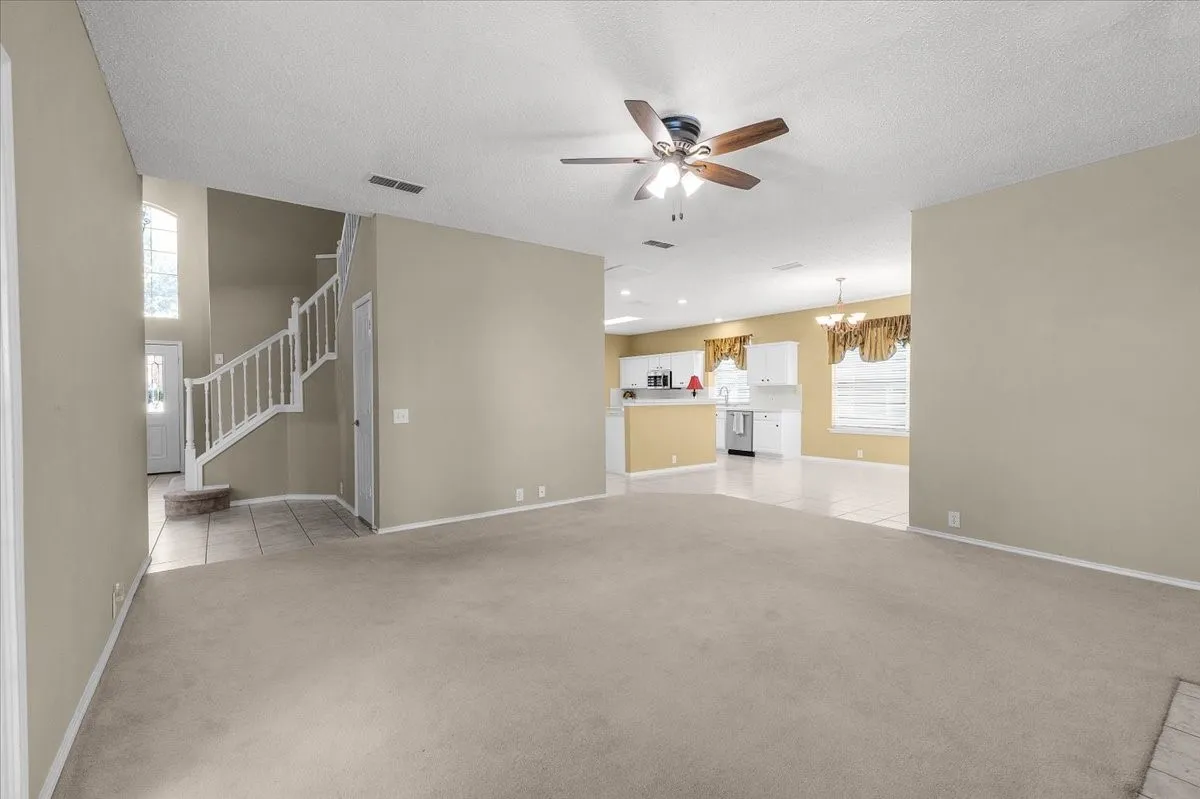Spacious interior with neutral walls, carpeted living area, and a ceiling fan