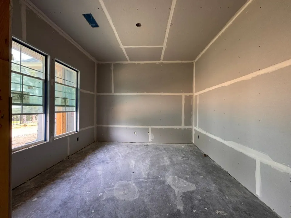 Unfinished interior space featuring two windows and drywall-finished walls