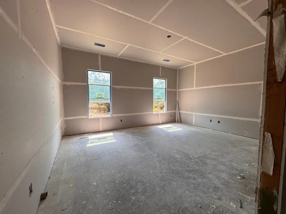 Spacious room featuring two windows, drywall installation, and a concrete floor