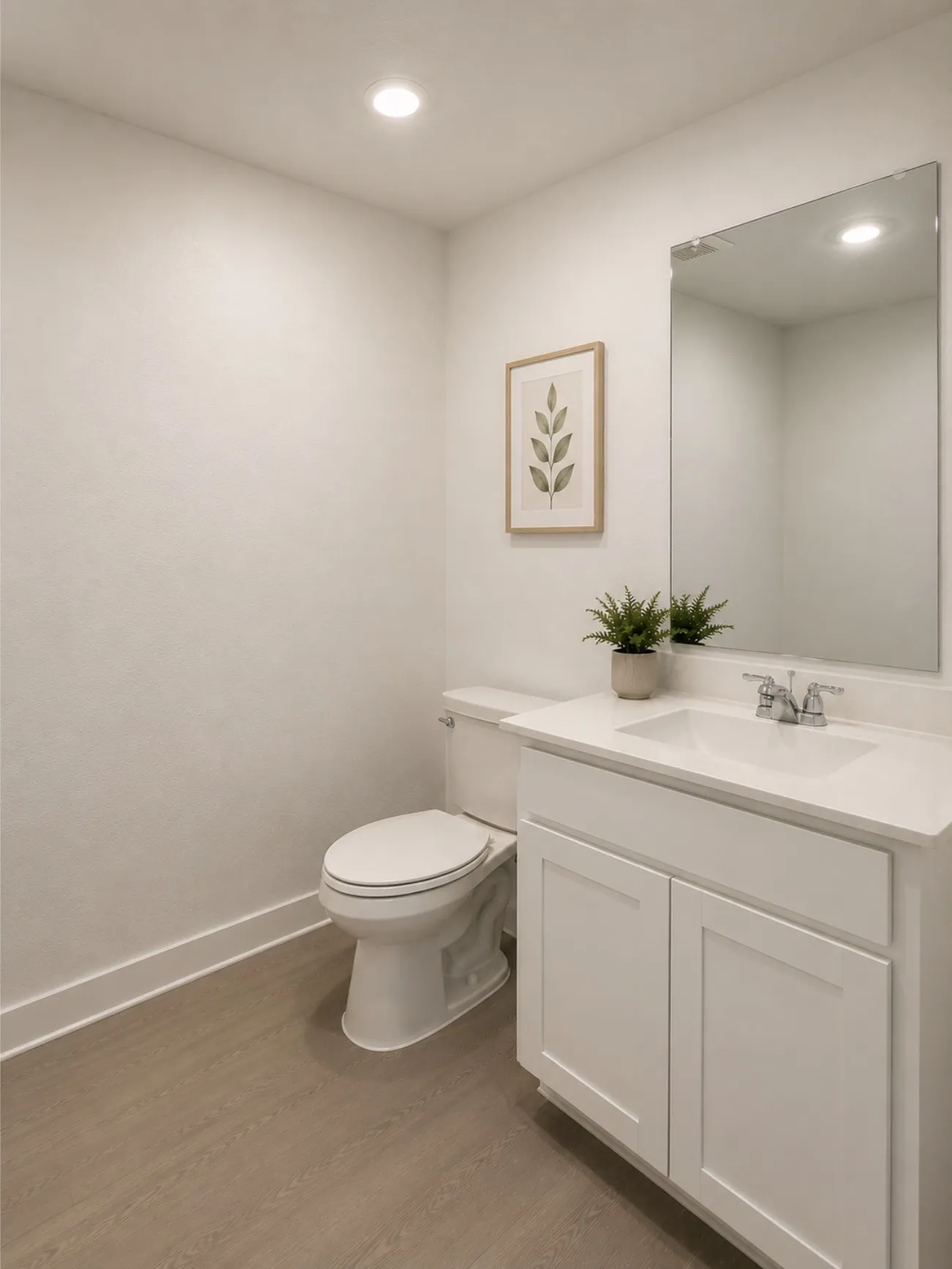 Powder room featuring a white single-sink vanity with a light-toned countertop, a rectangular mirror, a white toilet, and wood-finish flooring