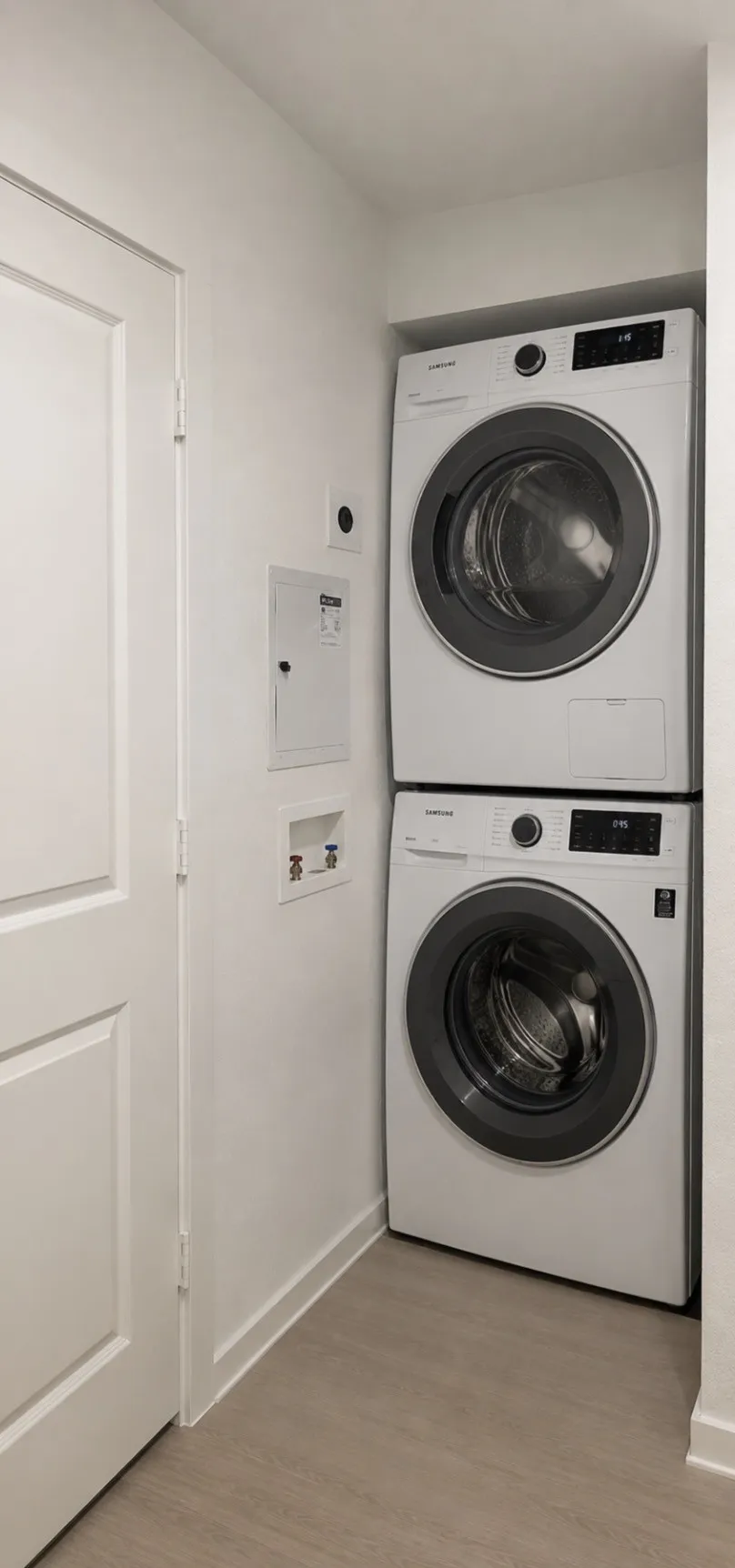 Dedicated laundry area featuring a stacked washer and dryer, wood-finish flooring, and a solid core door