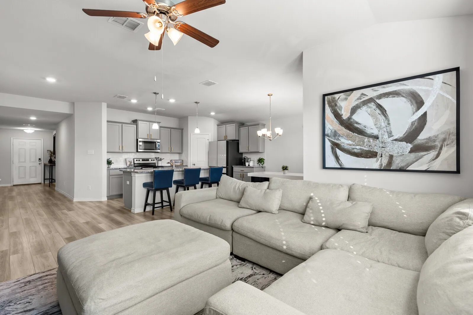 Open-concept living space with wood-finish flooring, recessed lighting, and a ceiling fan