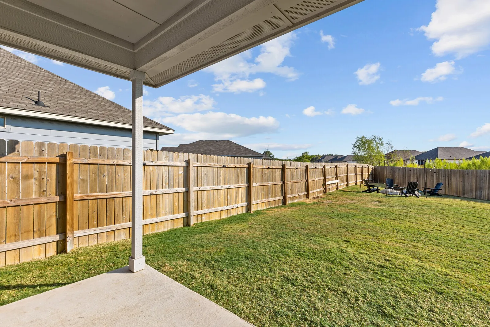 Expansive backyard featuring a privacy fence, concrete patio, and mature landscaping